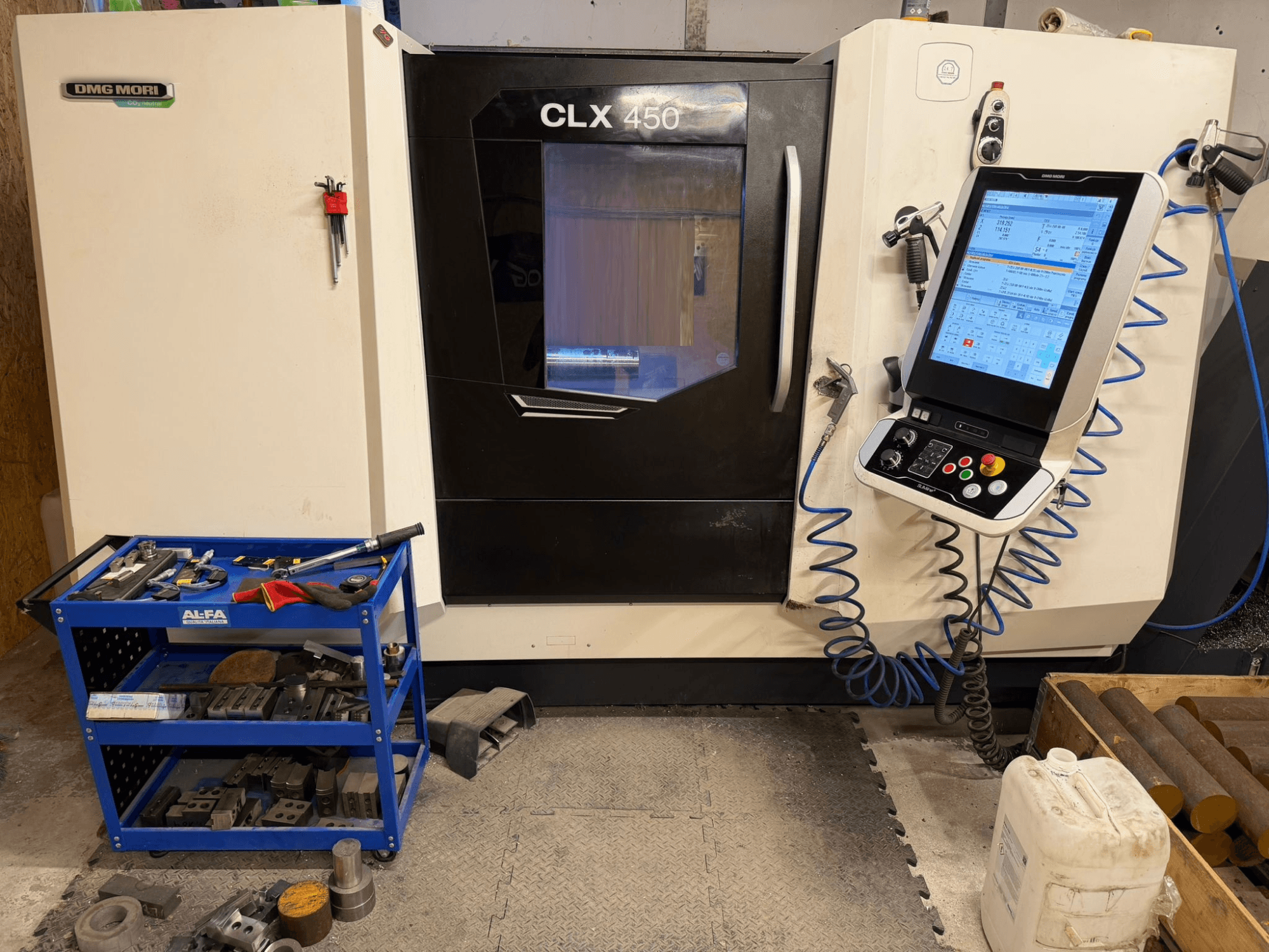 DMG MORI CLX 450 V3 yatay tornalama makinesinin önden görünümü, kontrol paneli ve yanında ekipman bulunan takım arabası.