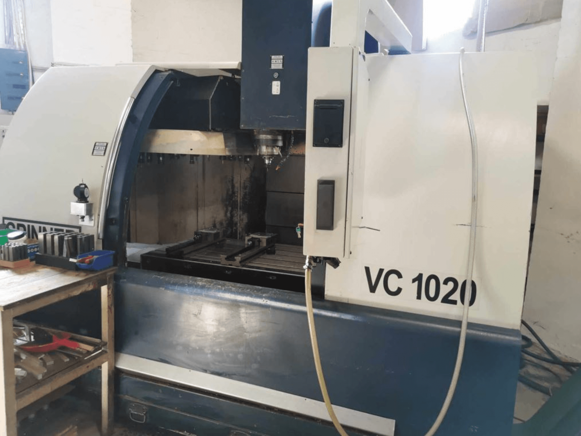 SPINNER VC 1020 dikey işleme merkezinin önden görünümü; yan taraftaki çalışma alanı ve kumanda paneli gösterilmiştir.