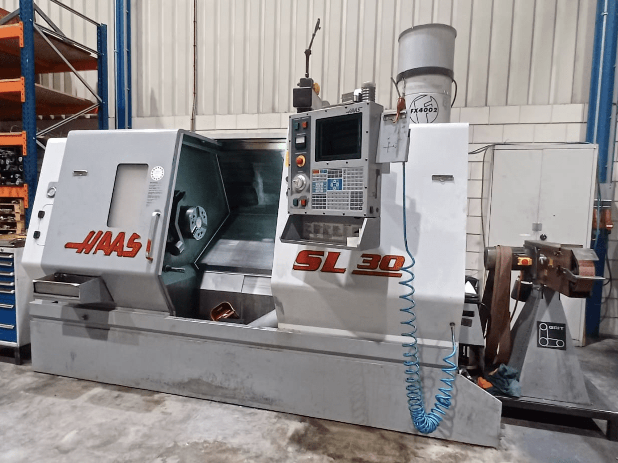 Haas SL 30 CNC torna tezgahının yandan görünümü, kontrol paneli, işleme alanı ve metal işleme için entegre edilmiş soğutma sistemi.