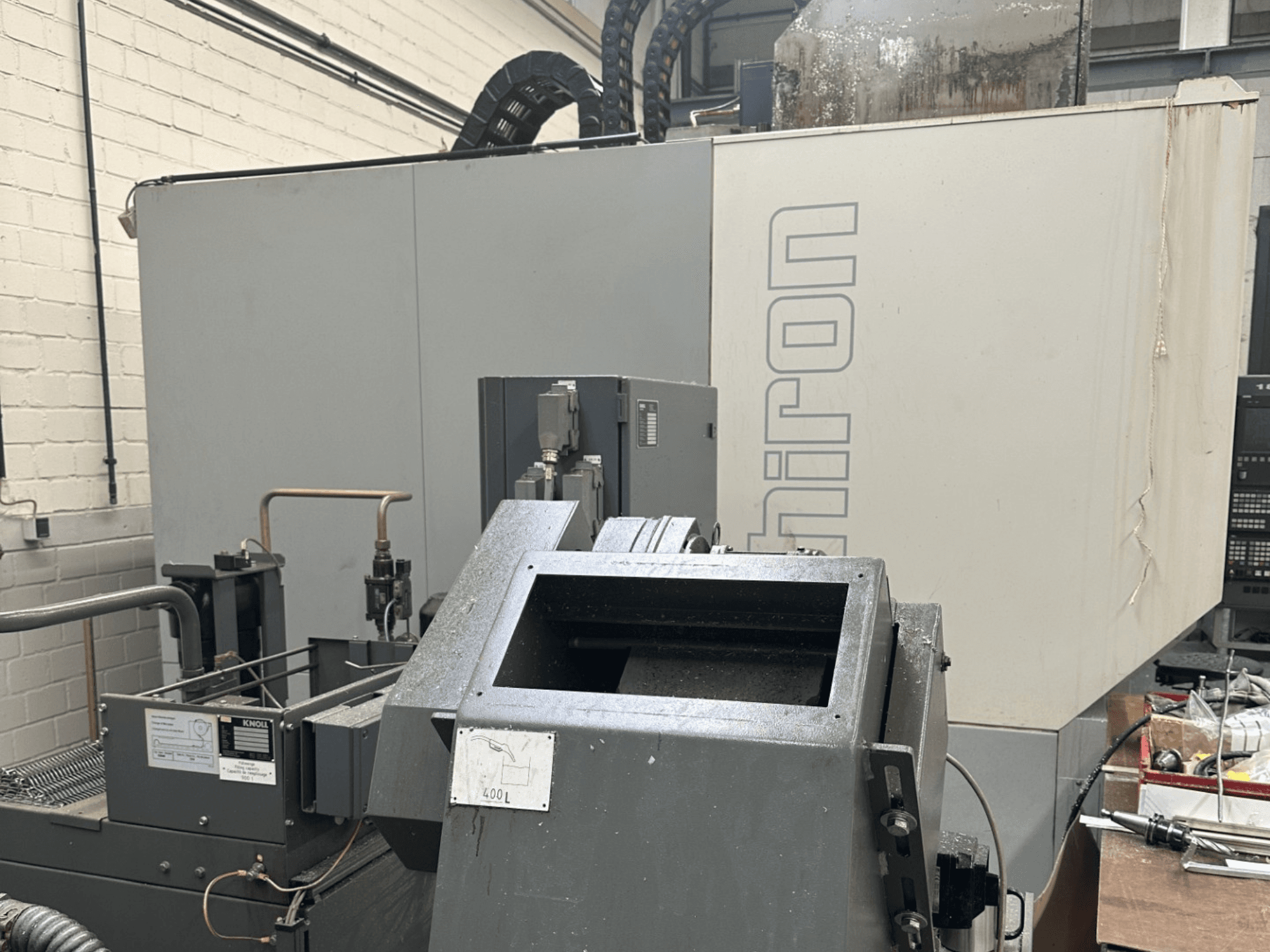 MARKA: Chiron; Gri dış yüzeyli, kontrol paneli görünen ve makine bileşenleri odakta olan endüstriyel CNC makinesinin önden görünümü.