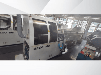 DECO 10a CNC makinesi atölyede, önden görünüm, kontrol paneli ve egzoz sistemini gösteriyor. Sağlam yapı ve hassas aletlere sahiptir.