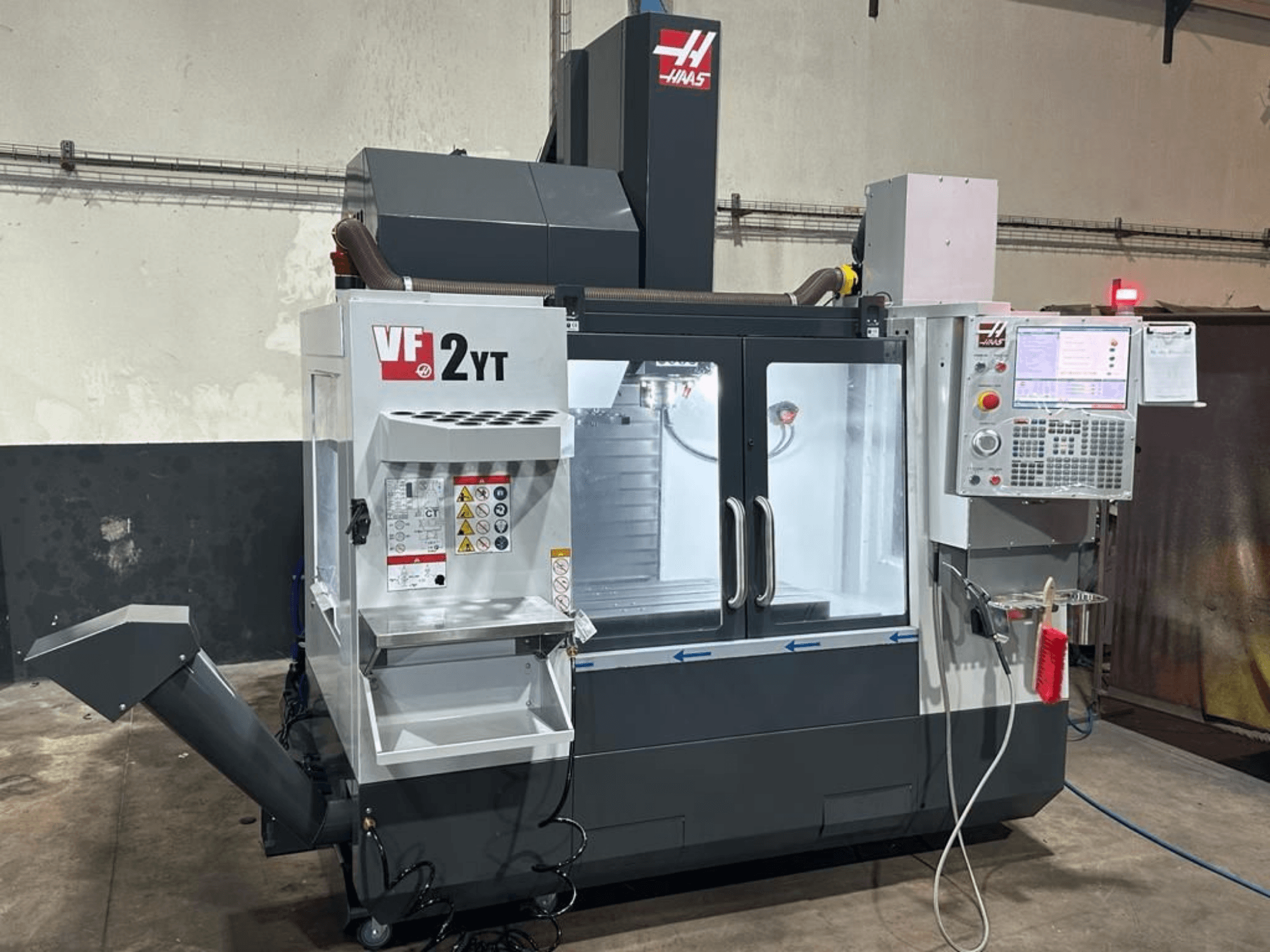 HAAS VF-2YT-EU dikey işleme merkezinin önden görünümü; kontrol paneli ve takım saklama bölmesi görülmektedir.