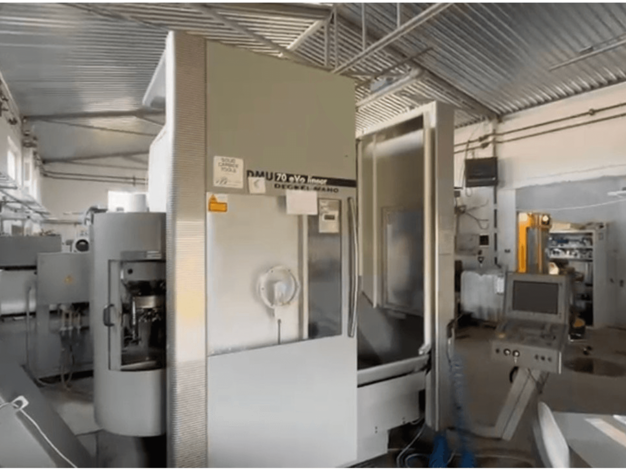 Bir atölyede DMU 70 eVo lineer CNC makinesi, önden görünüm, bir kontrol paneli ve modern bir tasarıma sahiptir.