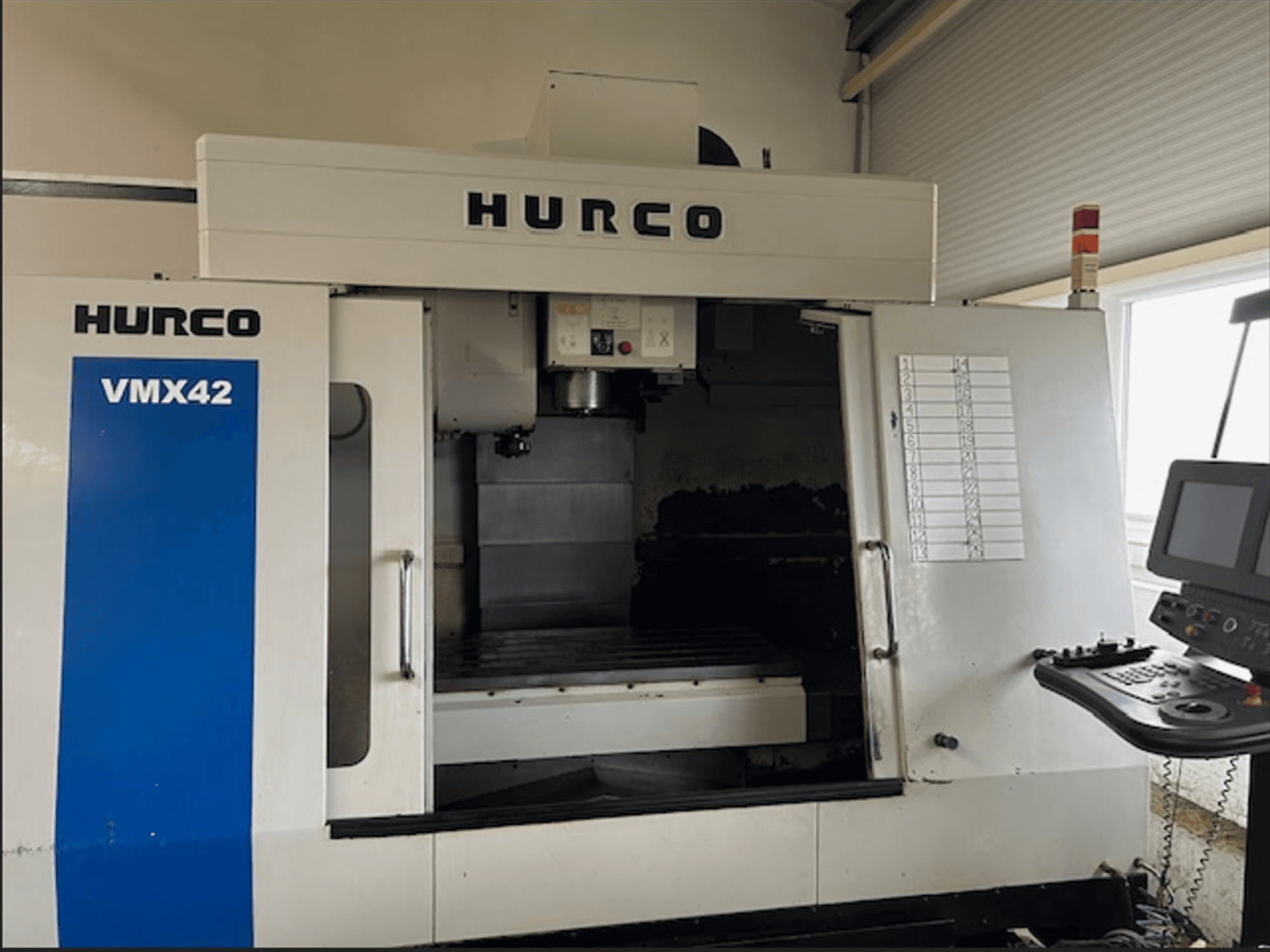 Hurco VMX42 CNC freze makinesi, önden görünüm, kontrol paneli ve işleme operasyonları için açık çalışma alanına sahiptir.