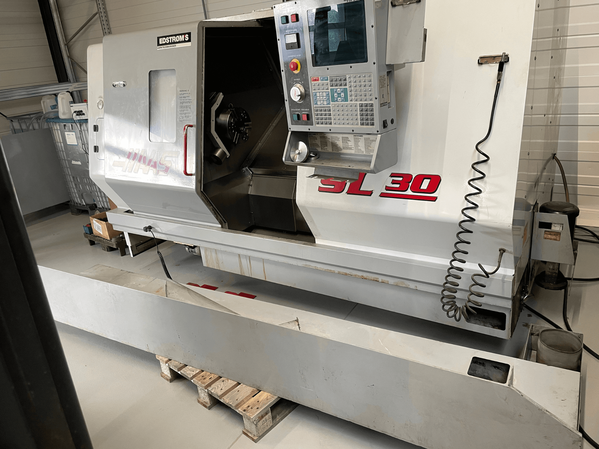 Atölyede Haas SL 30 CNC torna makinesi, yandan görünüm, kontrol paneli ve işleme görevleri için açık iş mili.
