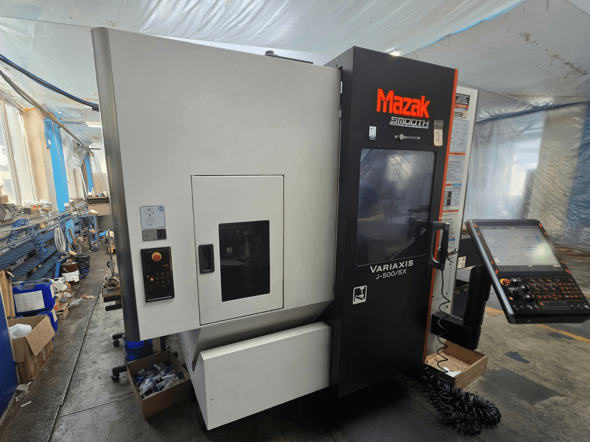 Mazak VARIAXIS J-500/5X dikey işleme merkezi; atölye ortamında yerleştirilmiş, kumandaları ve ekranı gösteren yandan görünüm.