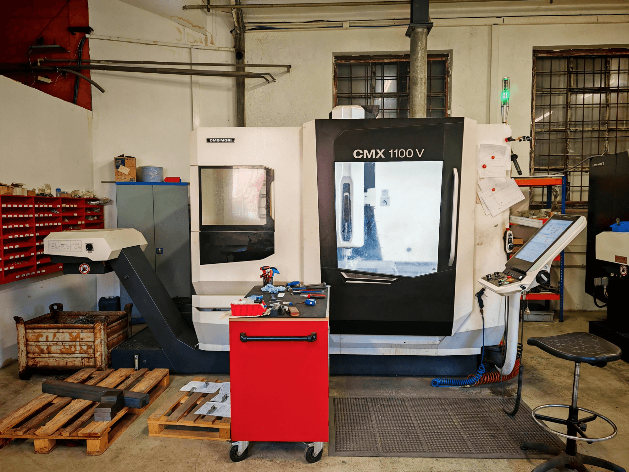 Atölyede bulunan DMG MORI CMX 1100 V dikey işleme merkezi, önden görünüm; kontrol paneli ve çevresindeki aletler görülmektedir.