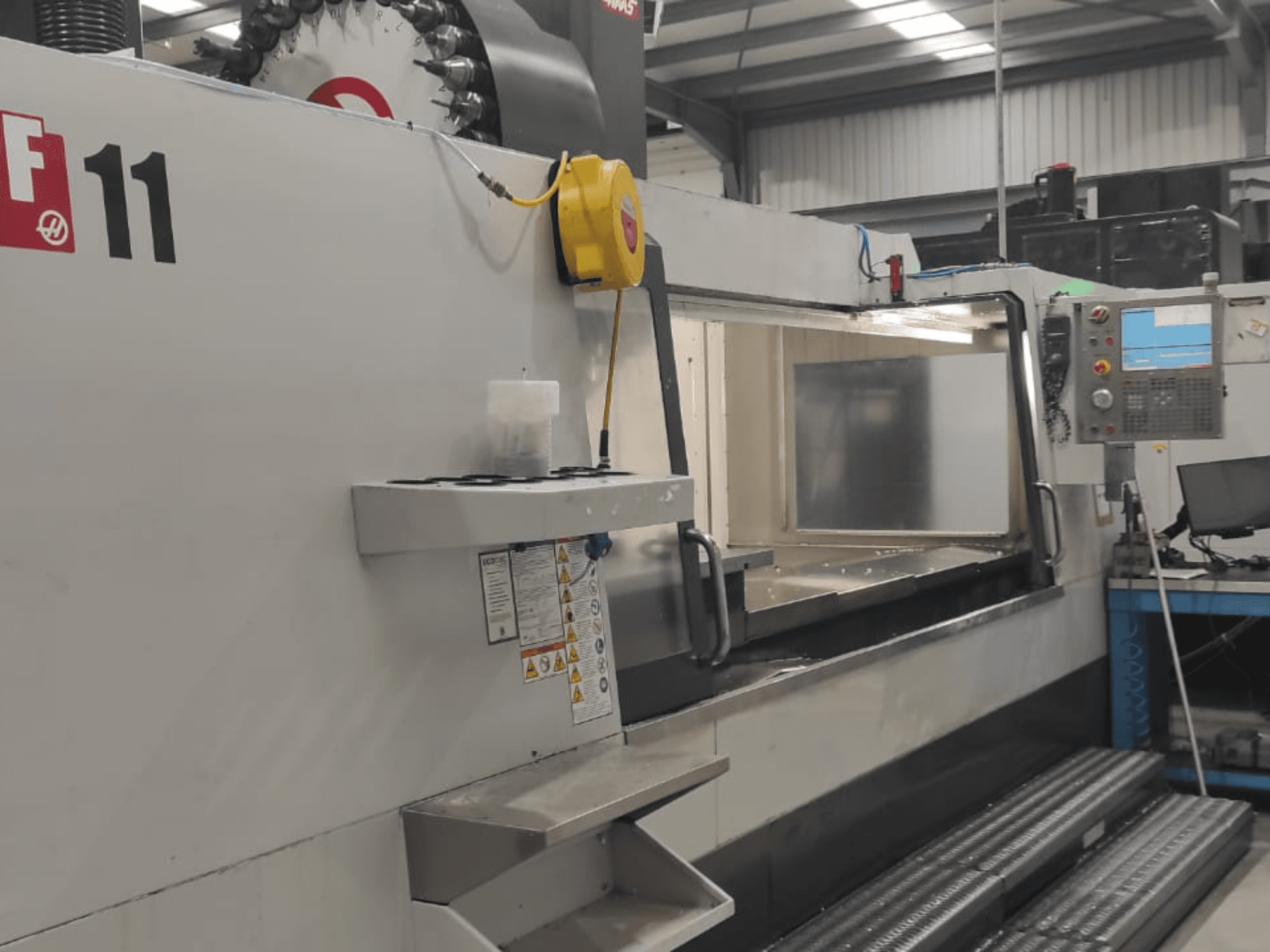 Haas'ın VF-11 model makinesi, kontrol paneli, geniş çalışma alanı ve güvenlik etiketleri görünür şekilde önden gösterilmiştir.