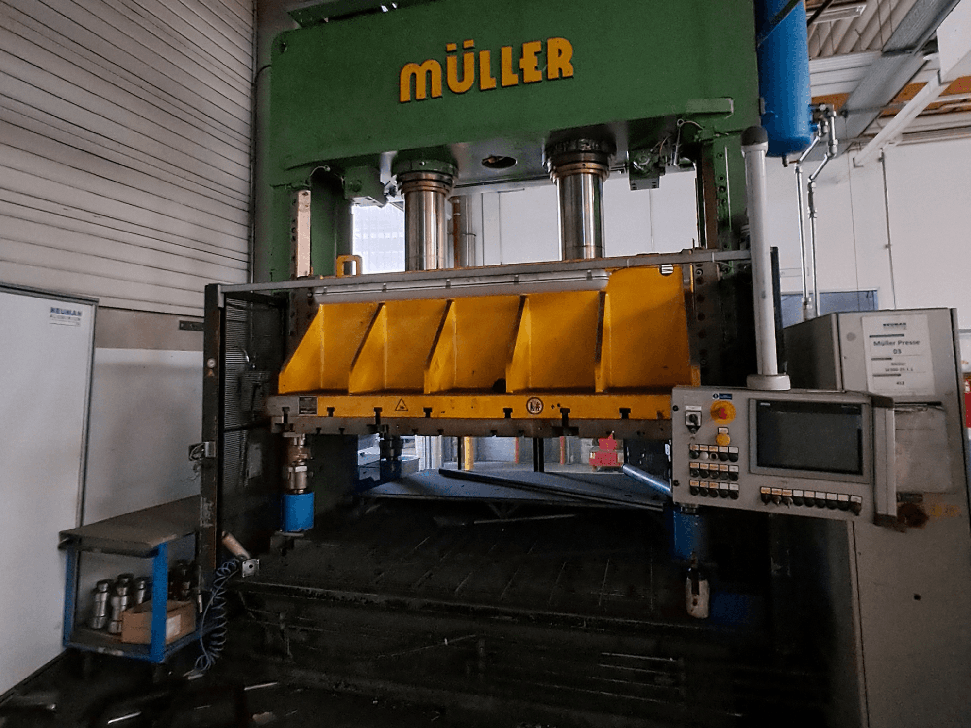 Sarı renkli pres bileşenleri ve yan tarafında bir kontrol paneli bulunan Müller SE 300-25.1.1 metal presinin önden görünümü.