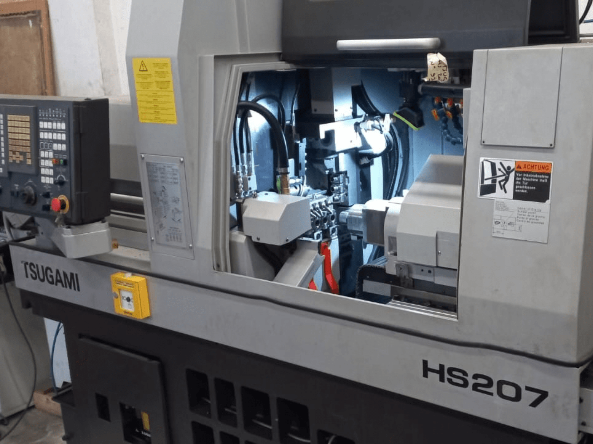 TSUGAMI HS207 İsviçre tipi torna tezgahı; kontrol paneli ve iç bileşenleri gösteren önden görünüm.