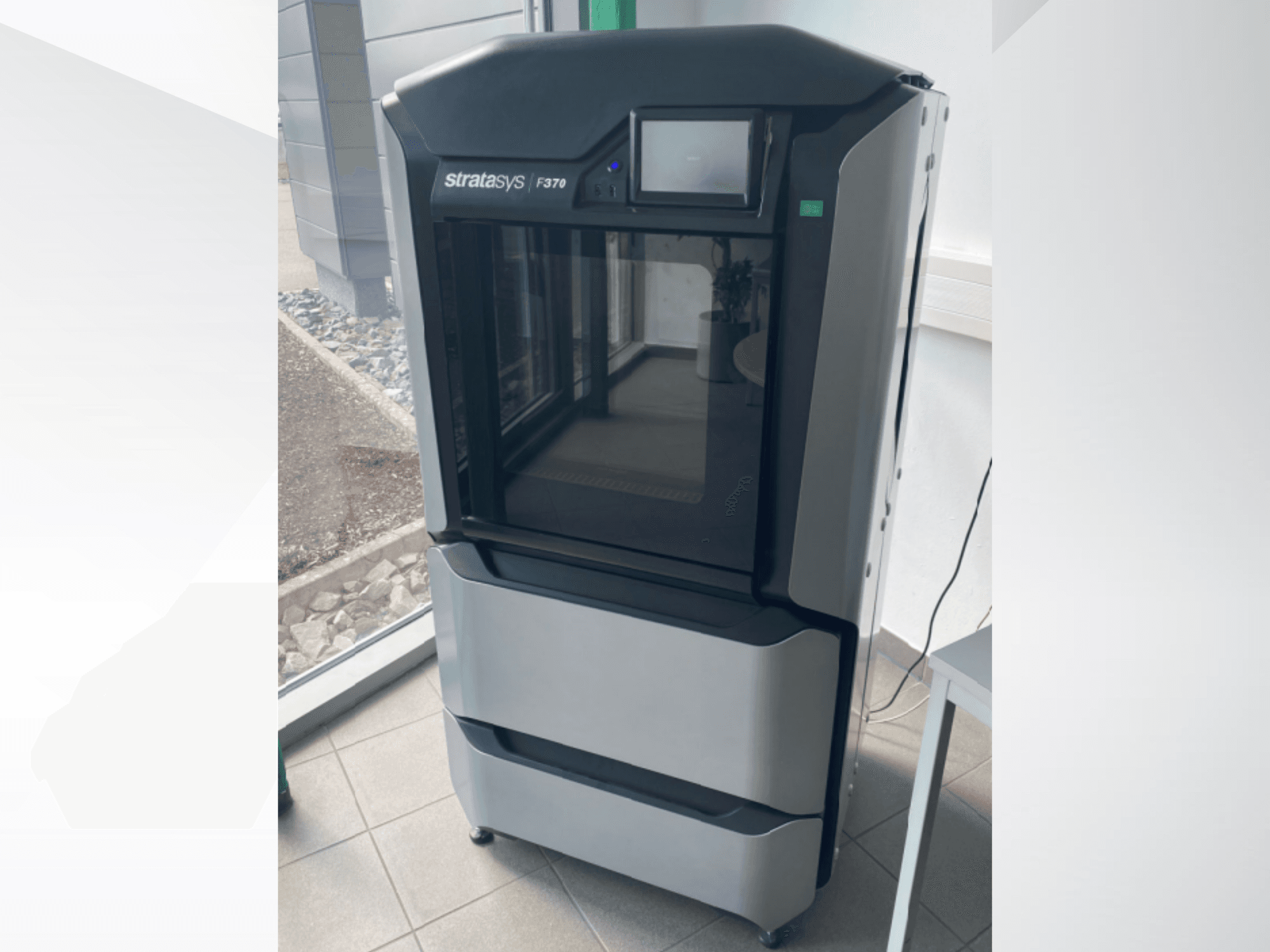 Stratasys F370 plastik 3D yazıcı, önden görünüm, dokunmatik ekranlı şık bir siyah ve gri tasarım sergiliyor.