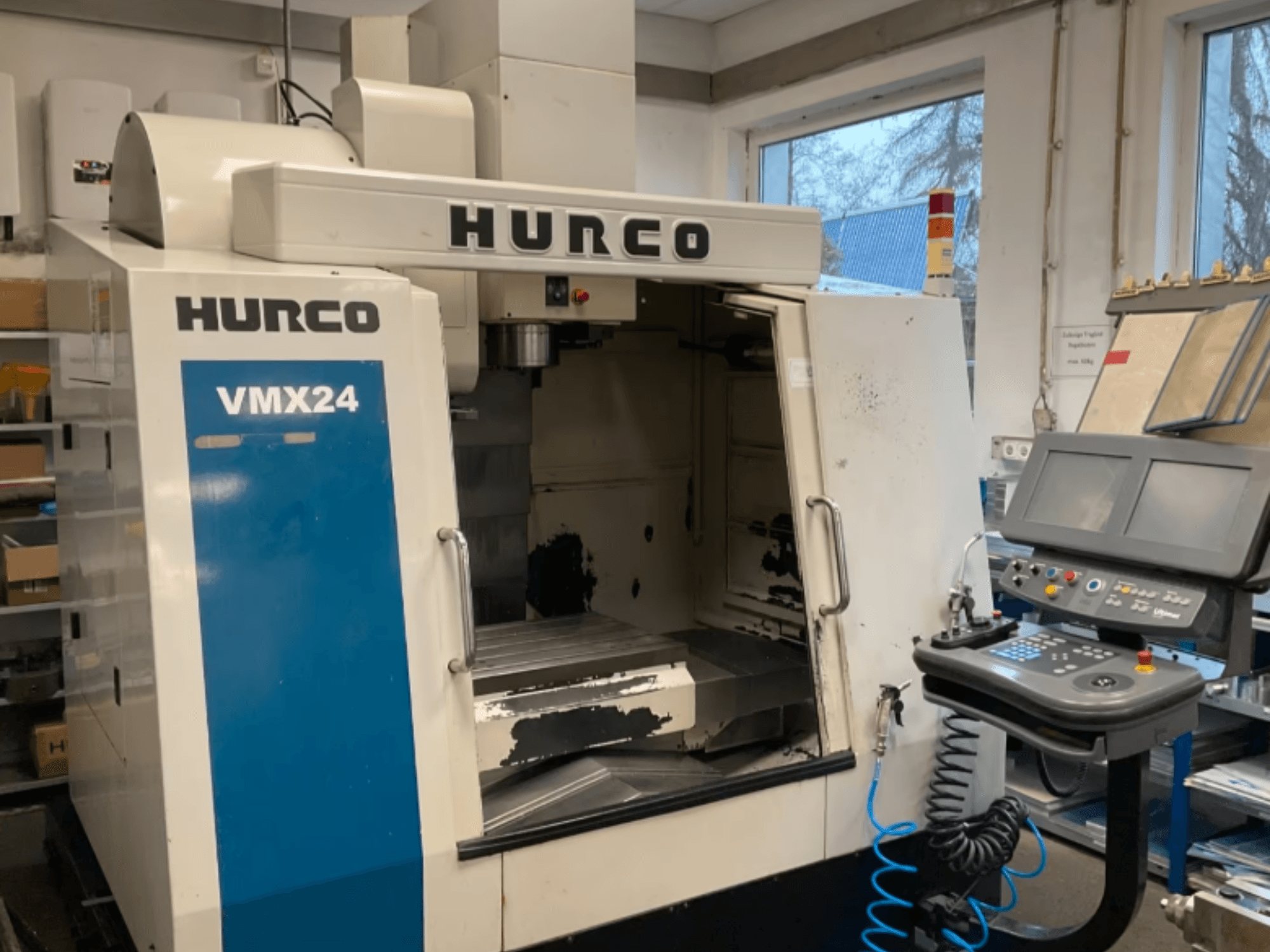 Hurco VMX24 Dikey İşleme Merkezi'nin önden görünümü; kontrol paneli, iş mili kafası ve işleme alanı görülmekte olup, bazı aşınma izleri mevcuttur.