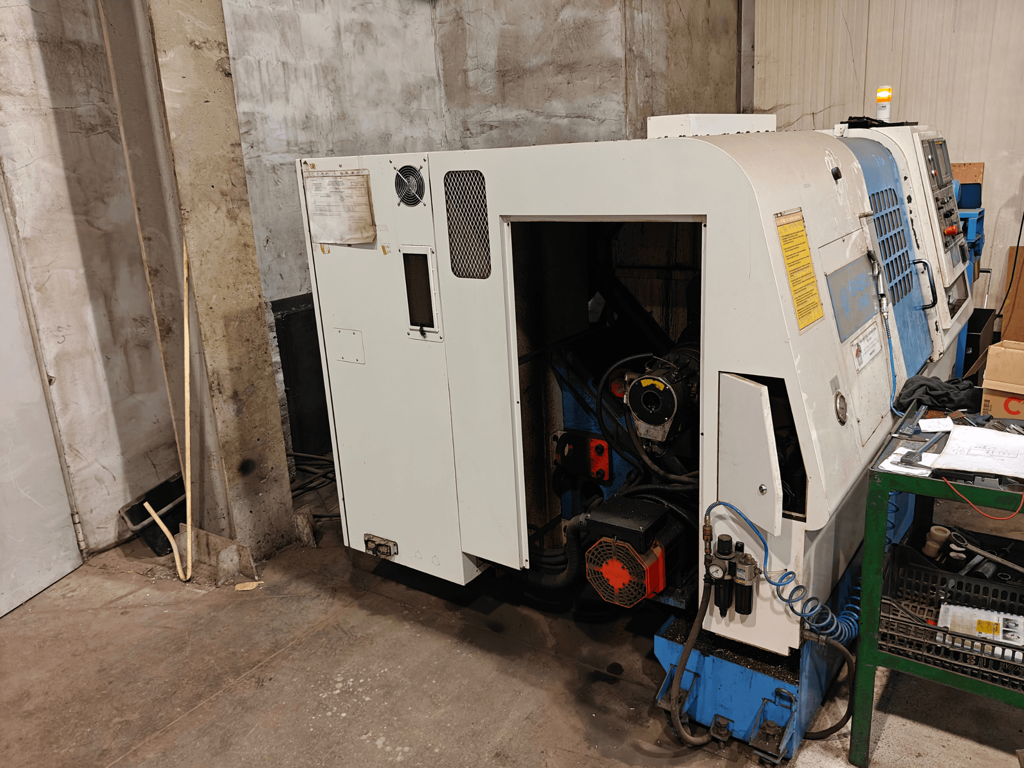 Marka ve modeli belirtilmemiş, kumandaları ve görünür motor bileşenleri olan bir torna makinesinin önden görünümü.