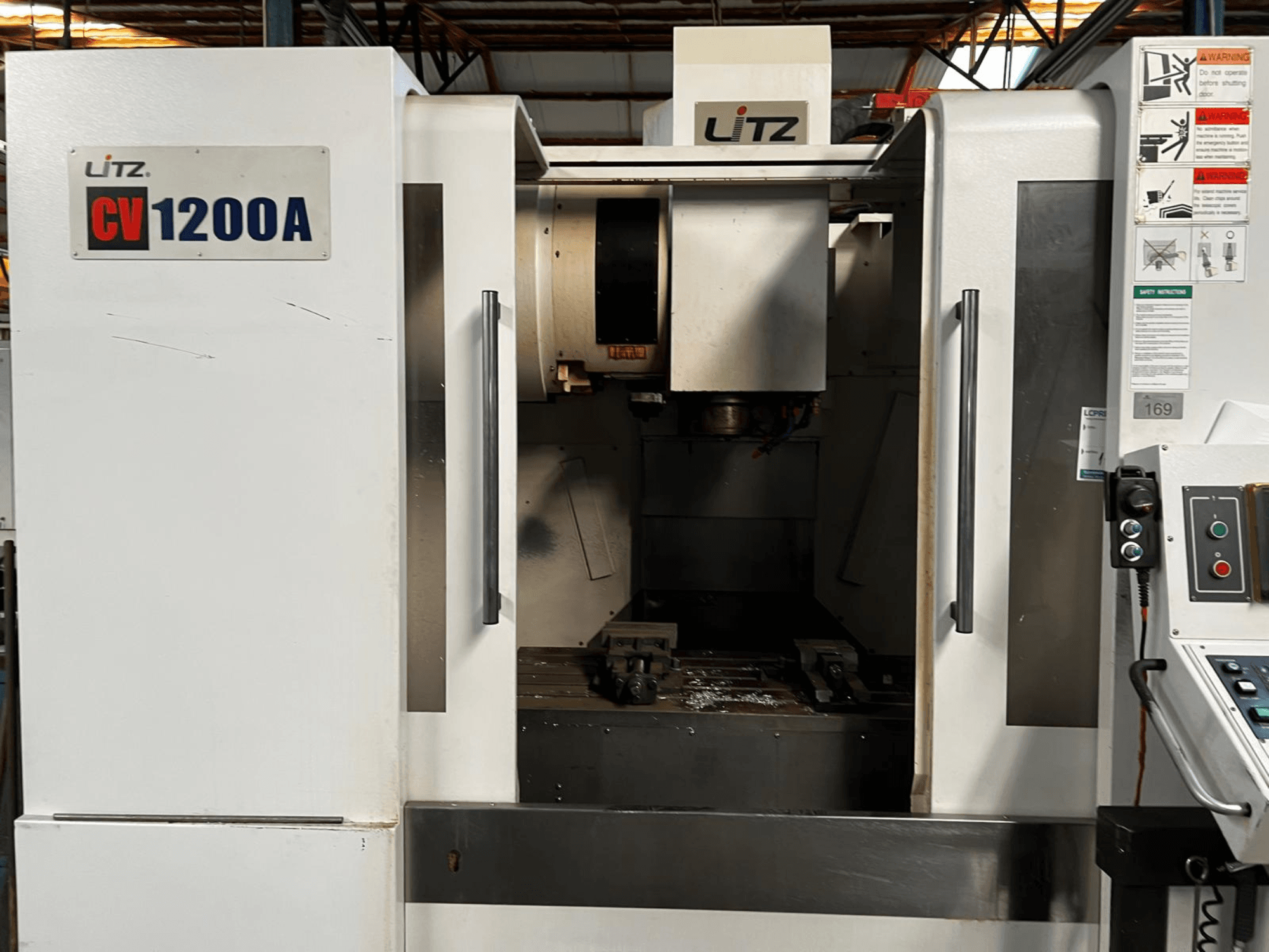 Litz CV1200A dikey işleme merkezi, önden görünüm; kontrol paneli, iş mili ve çalışma alanını ortaya çıkaran açık kapı görülmektedir.