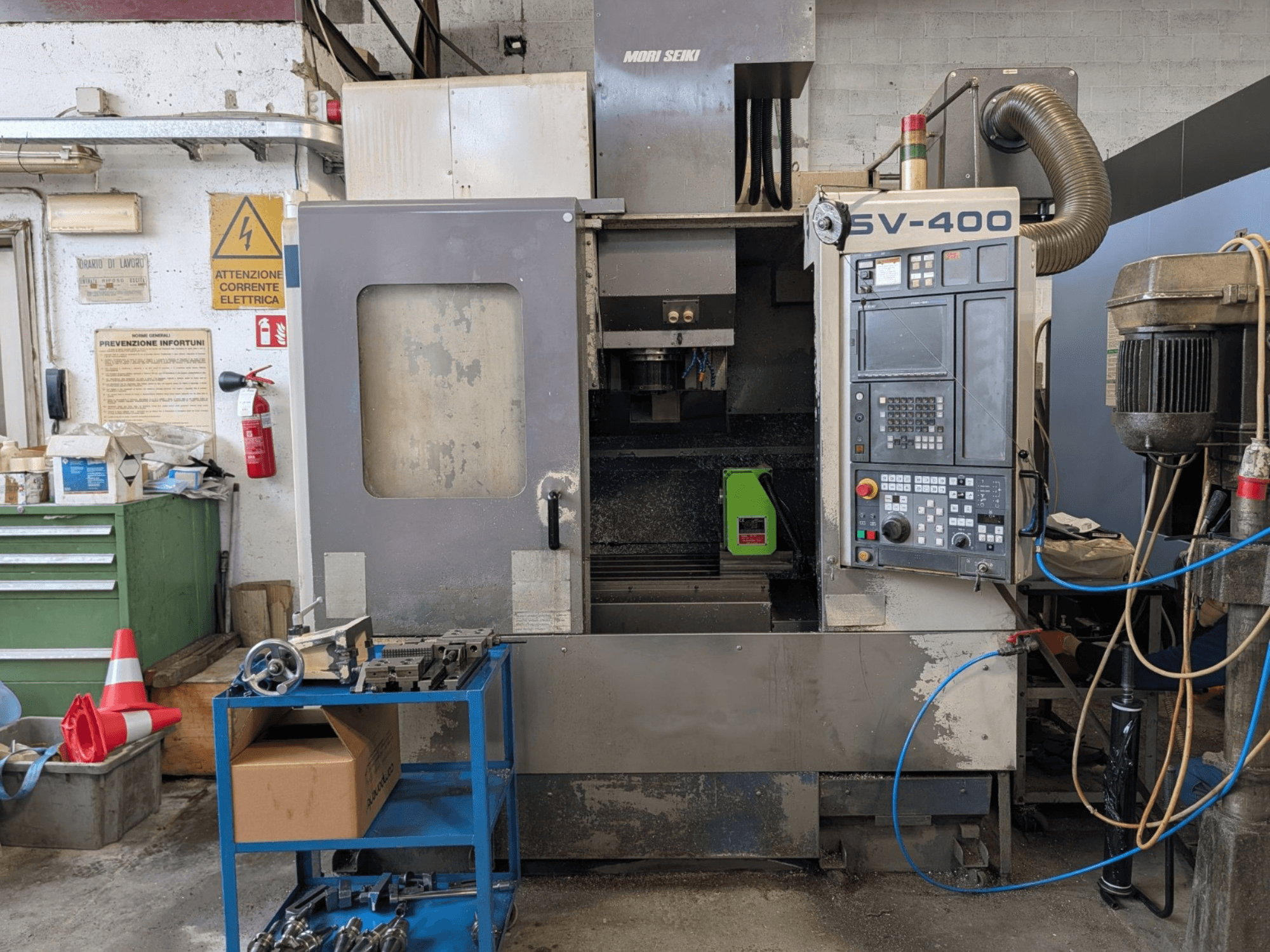 MORI SEIKI SV-400 dik işleme merkezi atölyede, yandan görünüm, kontrol paneli ve yakınındaki makine takımları sergileniyor.