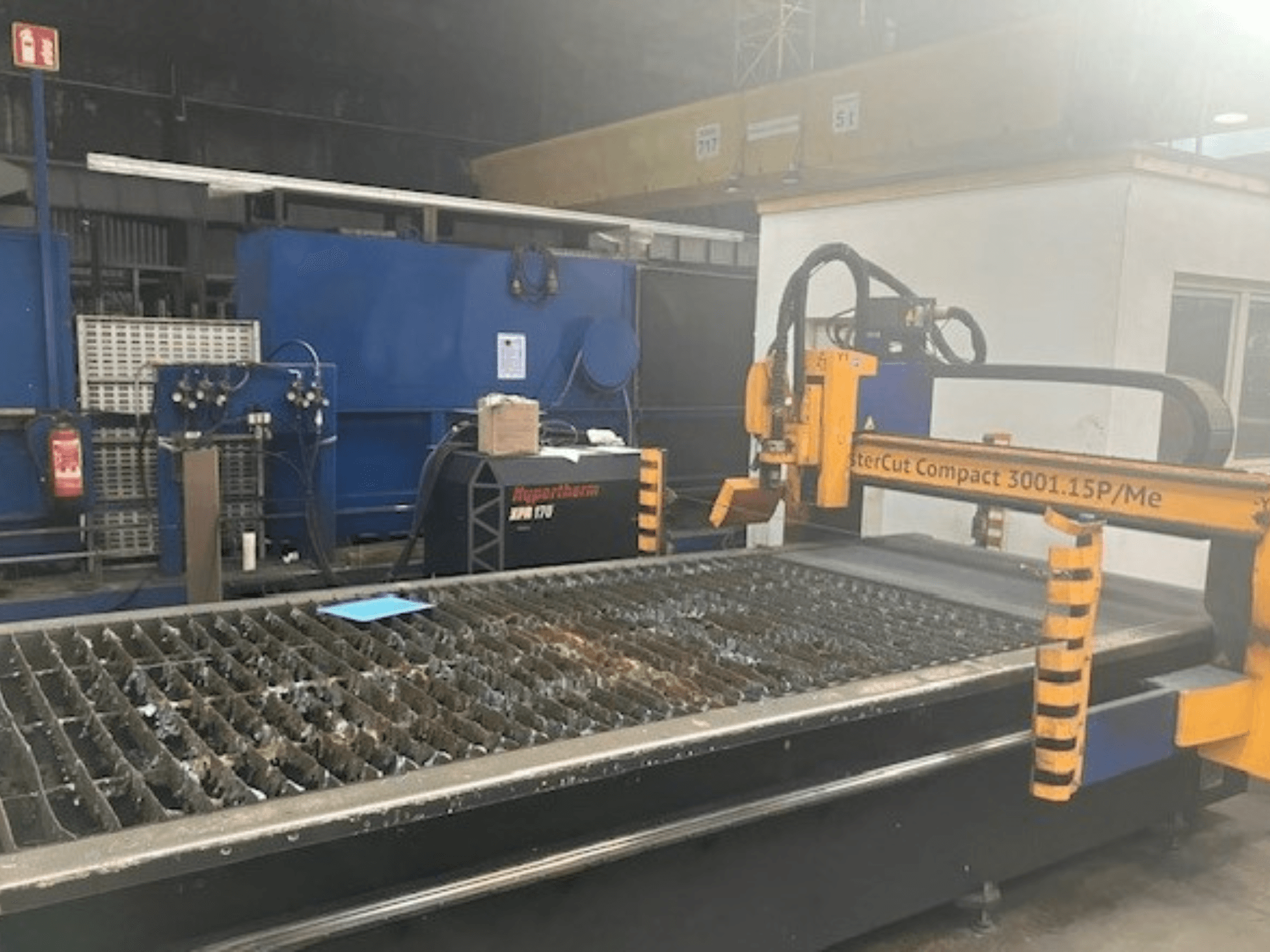 Hypertherm MasterCut Compact 3001.15P/Me plazma kesme makinesinin yandan görünümü, kesme tablası ve kontrol panelini gösterir.