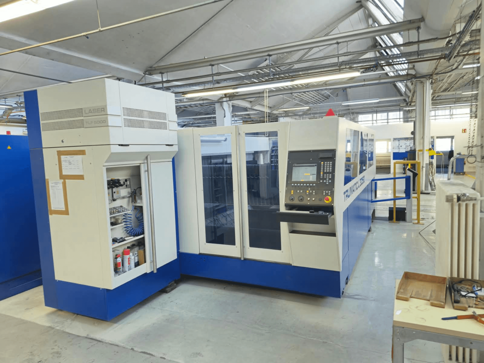 TRUMPF TruLaser L3050 CO₂ lazer kesim makinesi, kontrol paneli ve bakım erişim kapağı ile birlikte, fabrika ortamında çekilmiş önden görünüm.