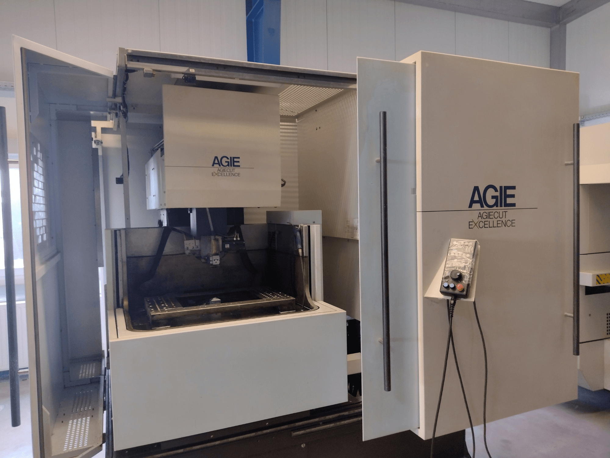 AGIE Progress 3 Tel EDM makinesinin önden görünümü; açık kabin, kontrol paneli ve kesme alanı görülmektedir.
