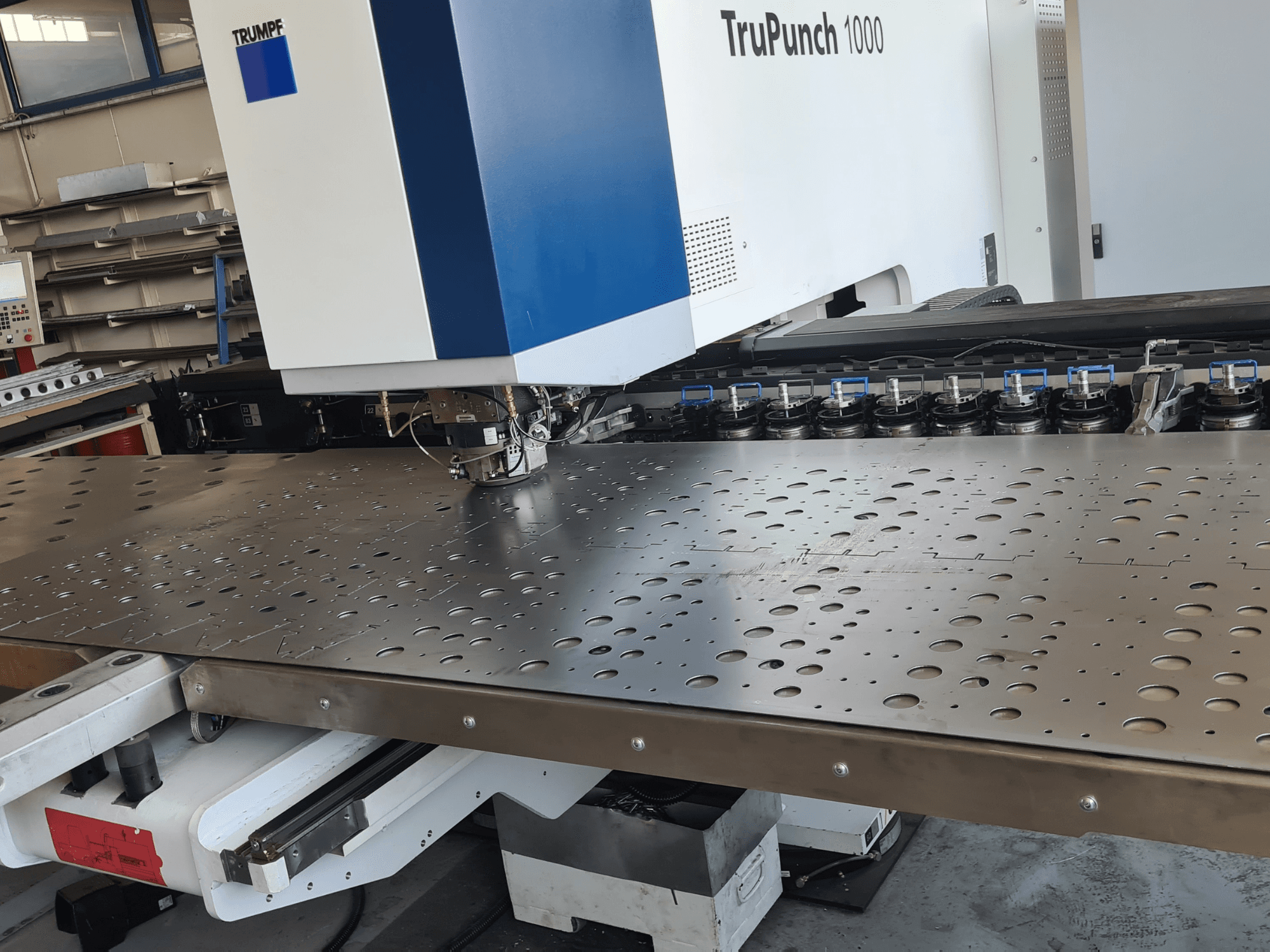 CNC delme makinesi TRUMPF TruPunch 1000, önden görünüm; delikli metal sac ve takım düzeni gösterilmektedir.