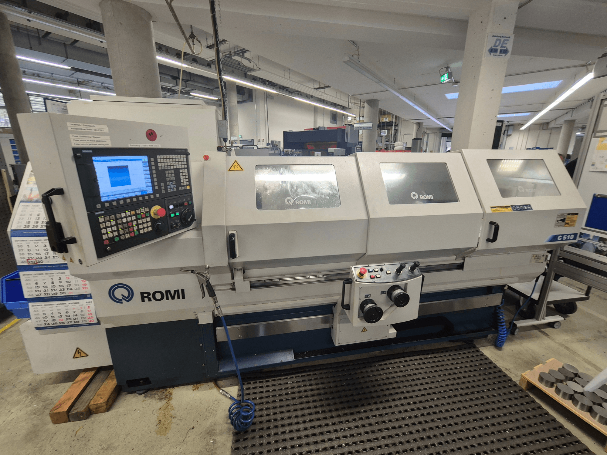 Romi C510 torna tezgahının önden görünümü, dijital kontrol paneli ve üç koruyucu kapak. Güvenlik uyarı etiketleri içerir.