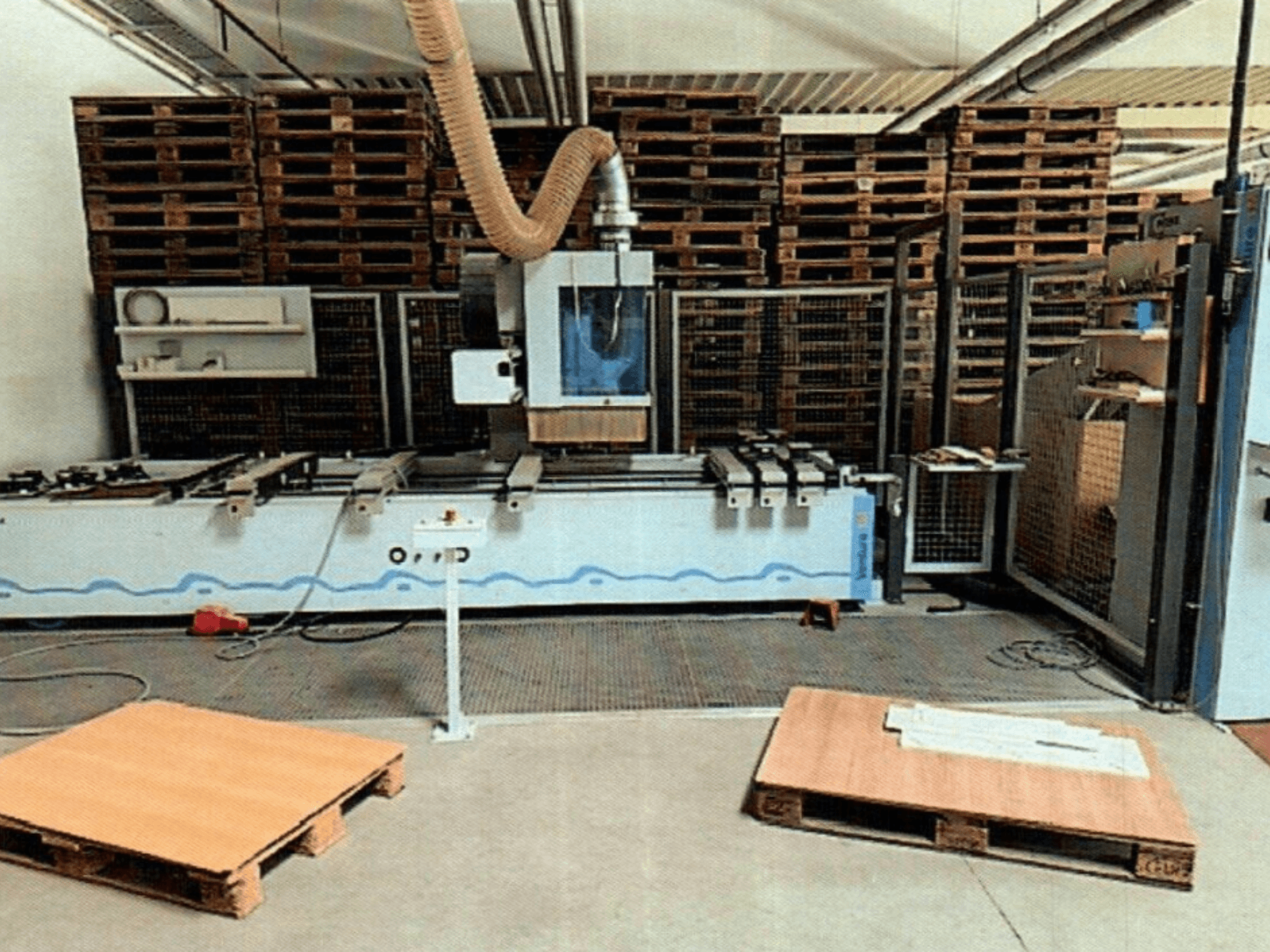 Atölyede CNC ahşap işleme merkezi Weeke Venture 1M, ahşap paletlerin göründüğü önden görünüm ve endüstriyel kurulum.