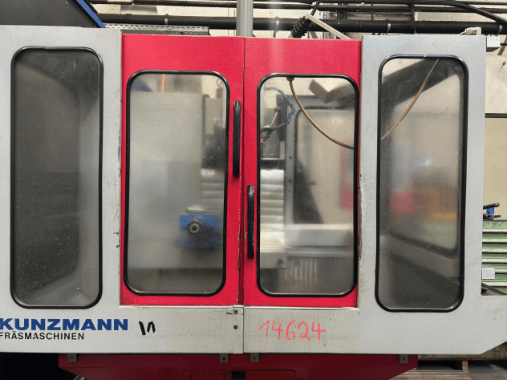 KUNZMANN CNC makinesi önden görünüm, kırmızı ve gri paneller, görünür bir kontrol paneli ve içinde takım tutucu.