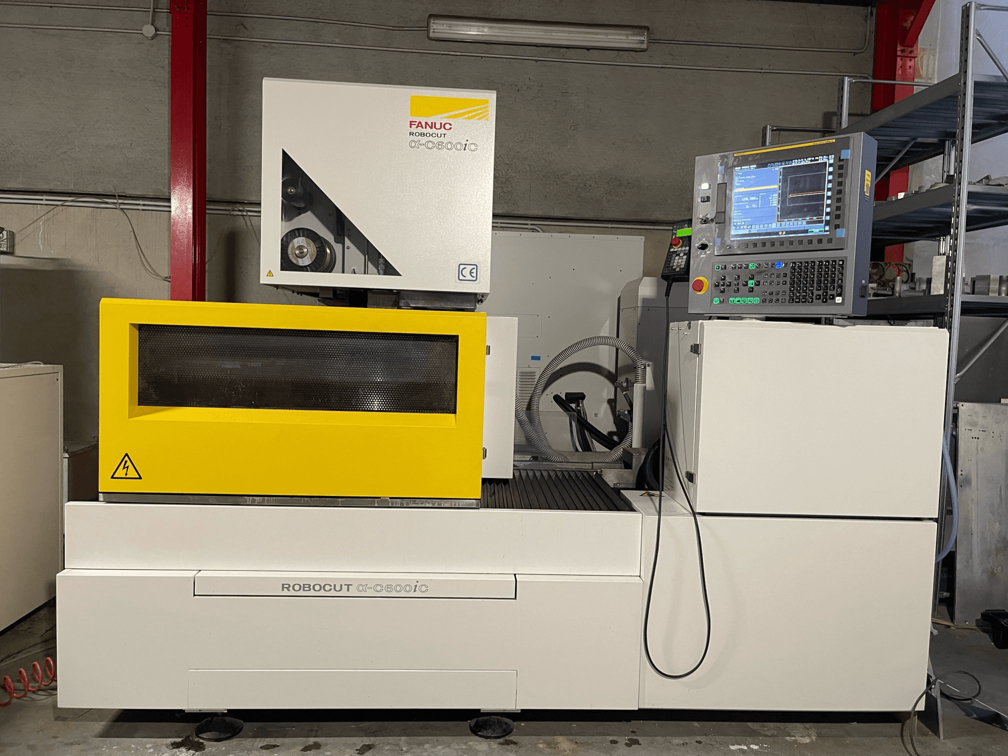 FANUC Robocut α-C600iC, sarı güvenlik kapağı ve kontrol paneli ile CNC makinesinin yandan görünümü, hassas kesim kabiliyetini sergiliyor.