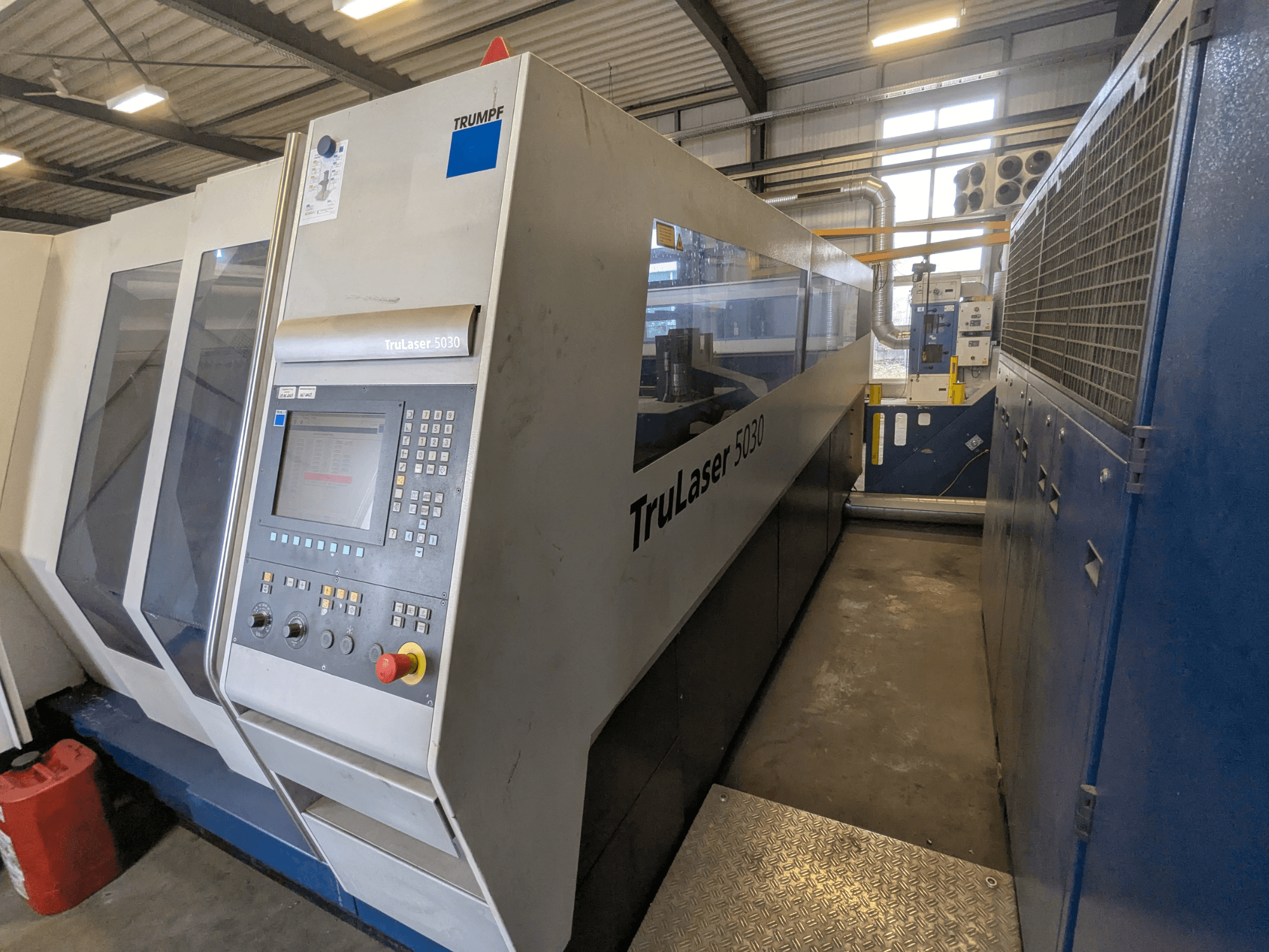 TRUMPF TruLaser 5030 CO2 lazer kesim makinesi, kontrol panelini ve şık tasarımı gösteren önden görünüm, endüstriyel ortamda.