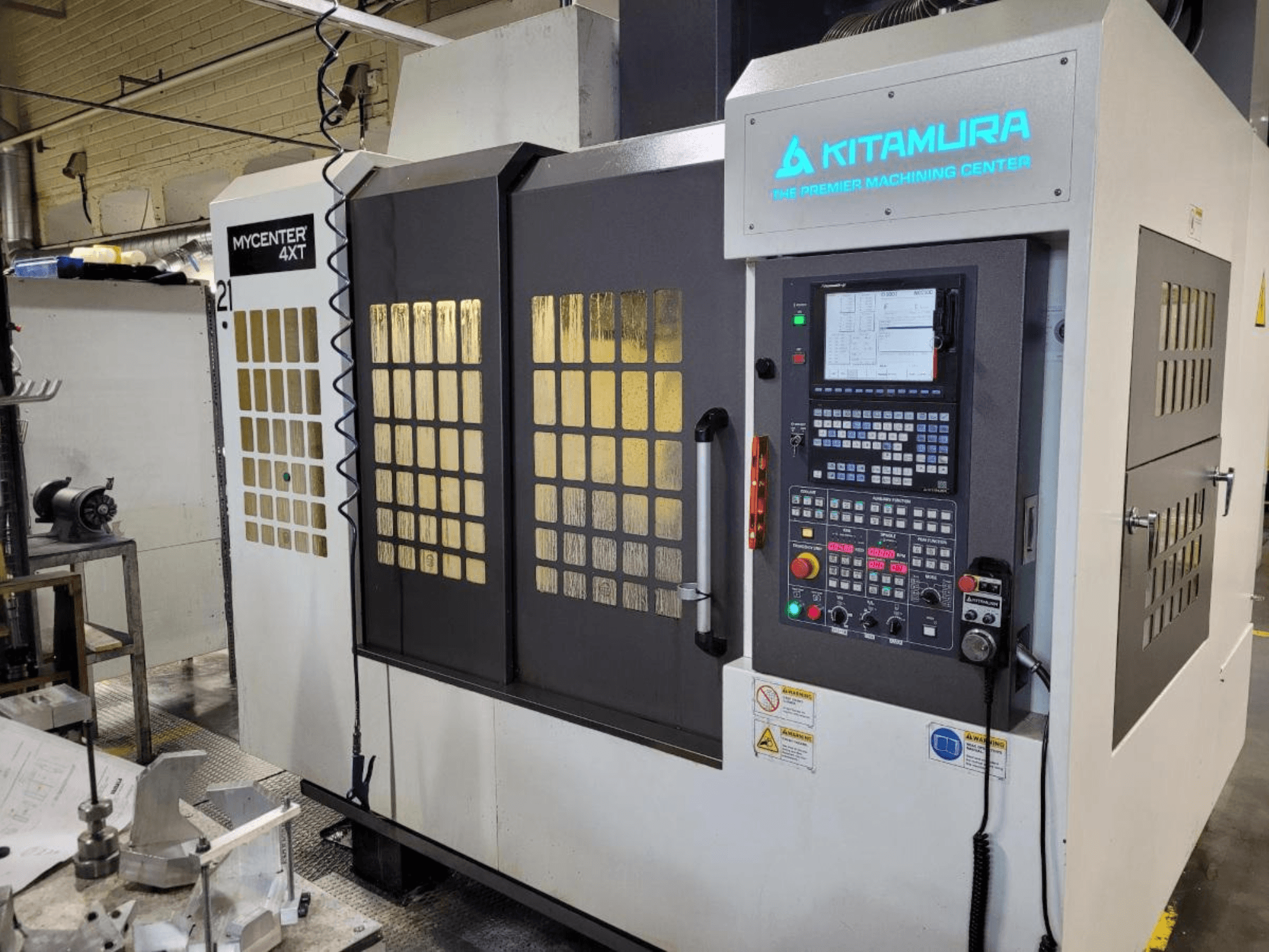 Bir Kitamura Mycenter-4XT işleme merkezinin kontrol paneli ve ışıklı markalama ile dikey görünümü.