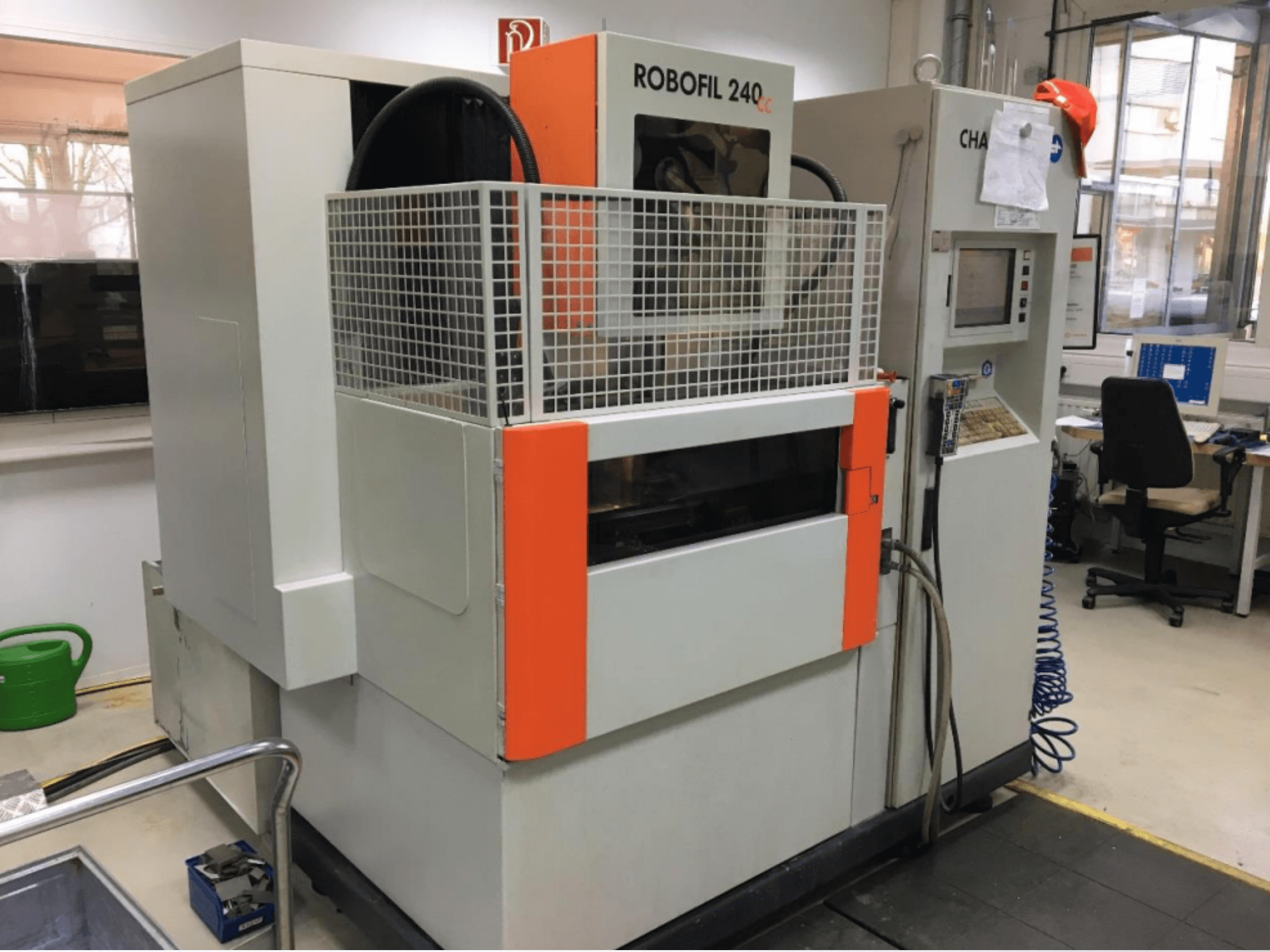 Bir atölyede bulunan, koruyucu ızgara ve kontrol paneli ile donatılmış CHARMILLES ROBOFIL 240 CC tel EDM makinesinin önden görünümü.