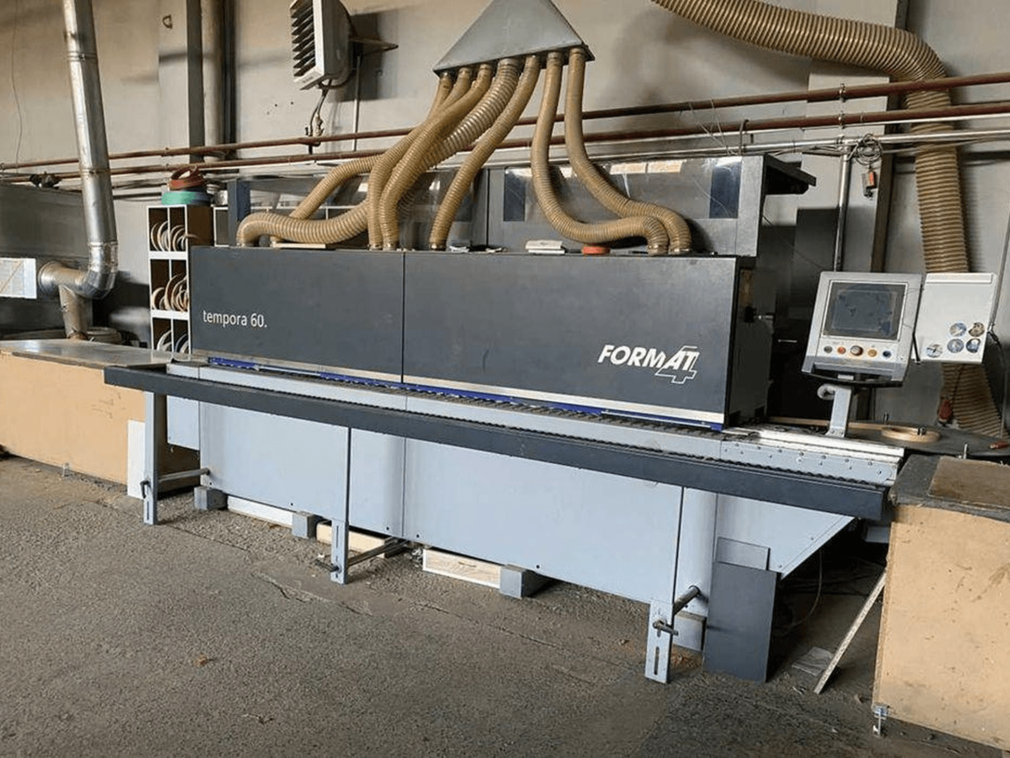 FORMAT4 Tempora 60 kenar bantlama makinesinin yandan görünümü, birden fazla hortum ve düğmeli ve ekranlı bir kontrol paneli içerir.