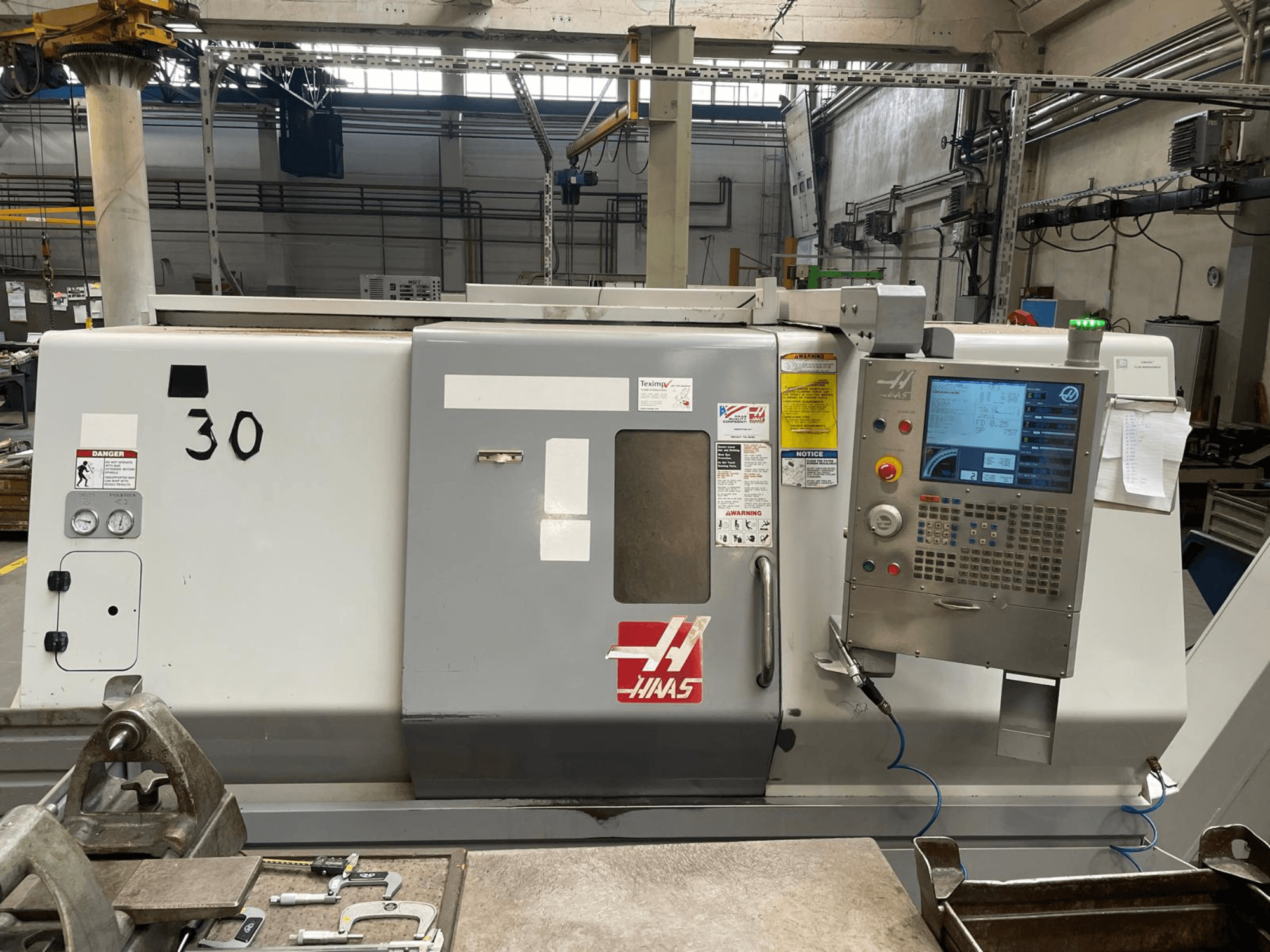 Haas SL-30THE yatay torna tezgahının önden görünümü; dijital kontrol paneli, tehlike etiketleri ve 30 model numarası görülmektedir.