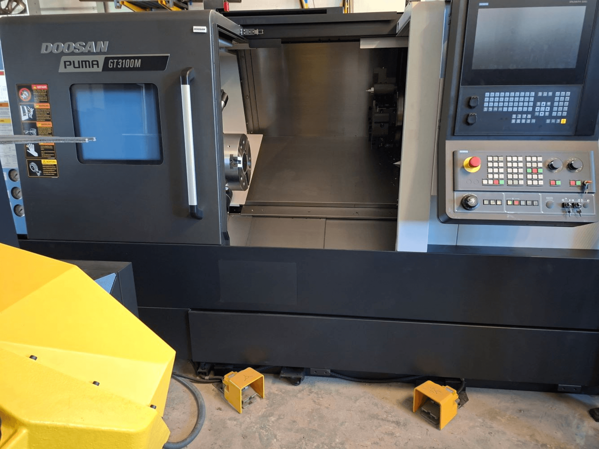 DOOSAN Puma GT 3100 M yatay torna makinesinin önden görünümü, kontrol paneli, açık taret ve iç çalışma alanı.