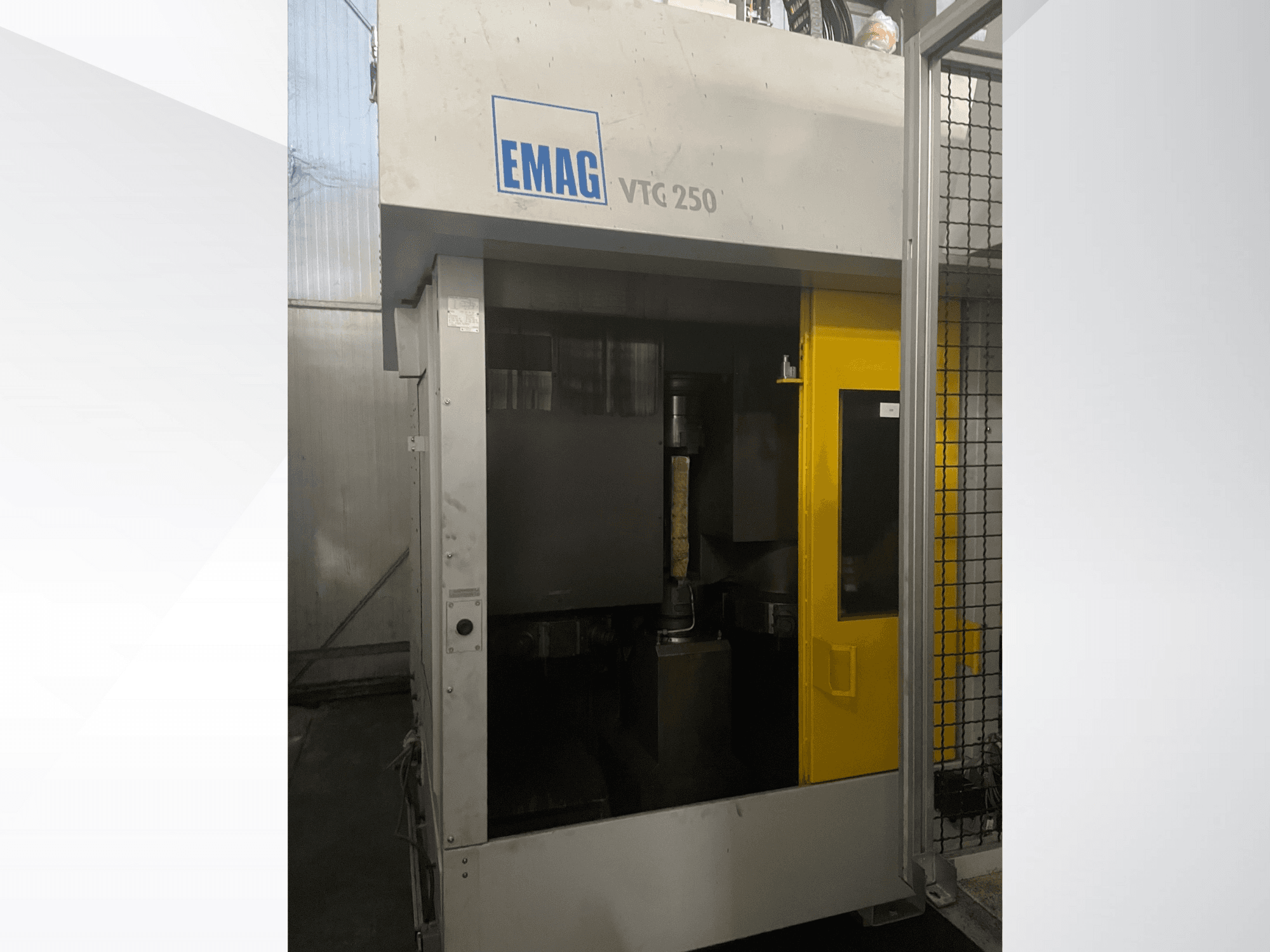 EMAG VTC 250 dikey işleme merkezinin önden görünümü, sarı bir kapı ve haznenin içinde görünür bir kesici takım.