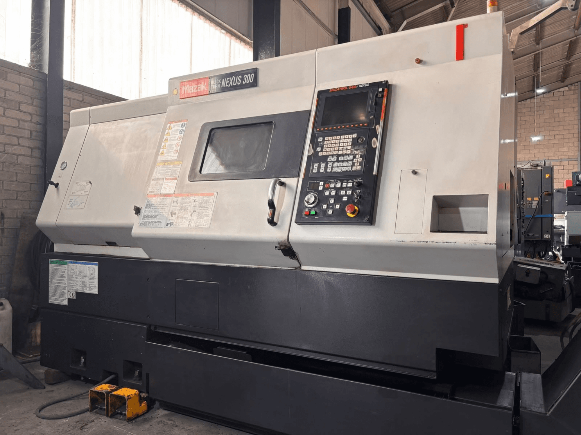 Mazak QT NEXUS 300 yatay torna tezgahı; atölye ortamında çekilmiş, kontrol paneli ve çalışma göstergelerini gösteren yan görünüm.