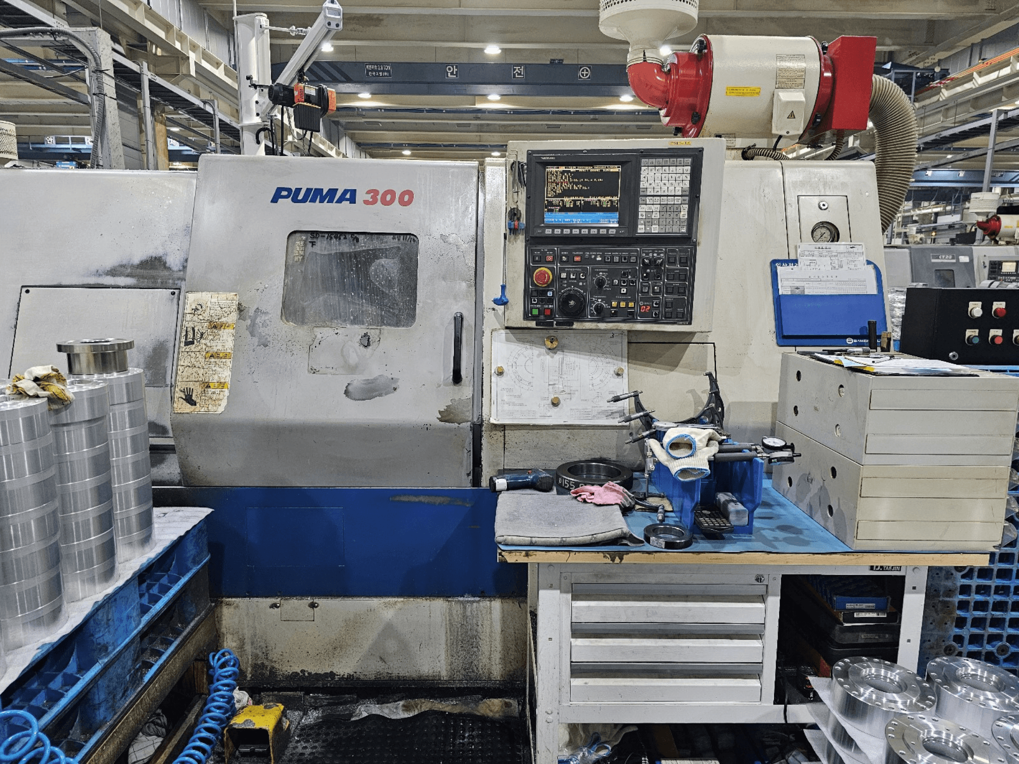 Bir atölyede PUMA 300 CNC makinesi; kontrol panelini, aletleri ve tezgah üzerindeki metal parçaları gösteren önden görünüm.