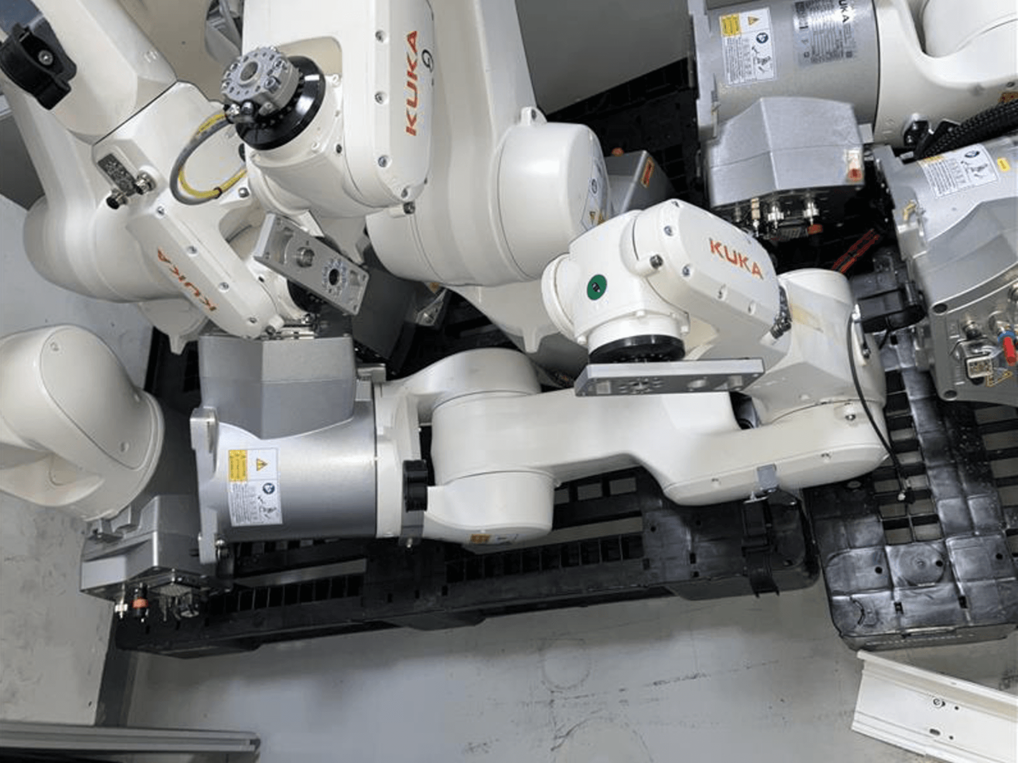 KUKA KR 6 R900 CR robot kolu üstten görünümde, çoklu eklemlere ve motorlara sahip, kablolarla siyah bir tabana monte edilmiştir.