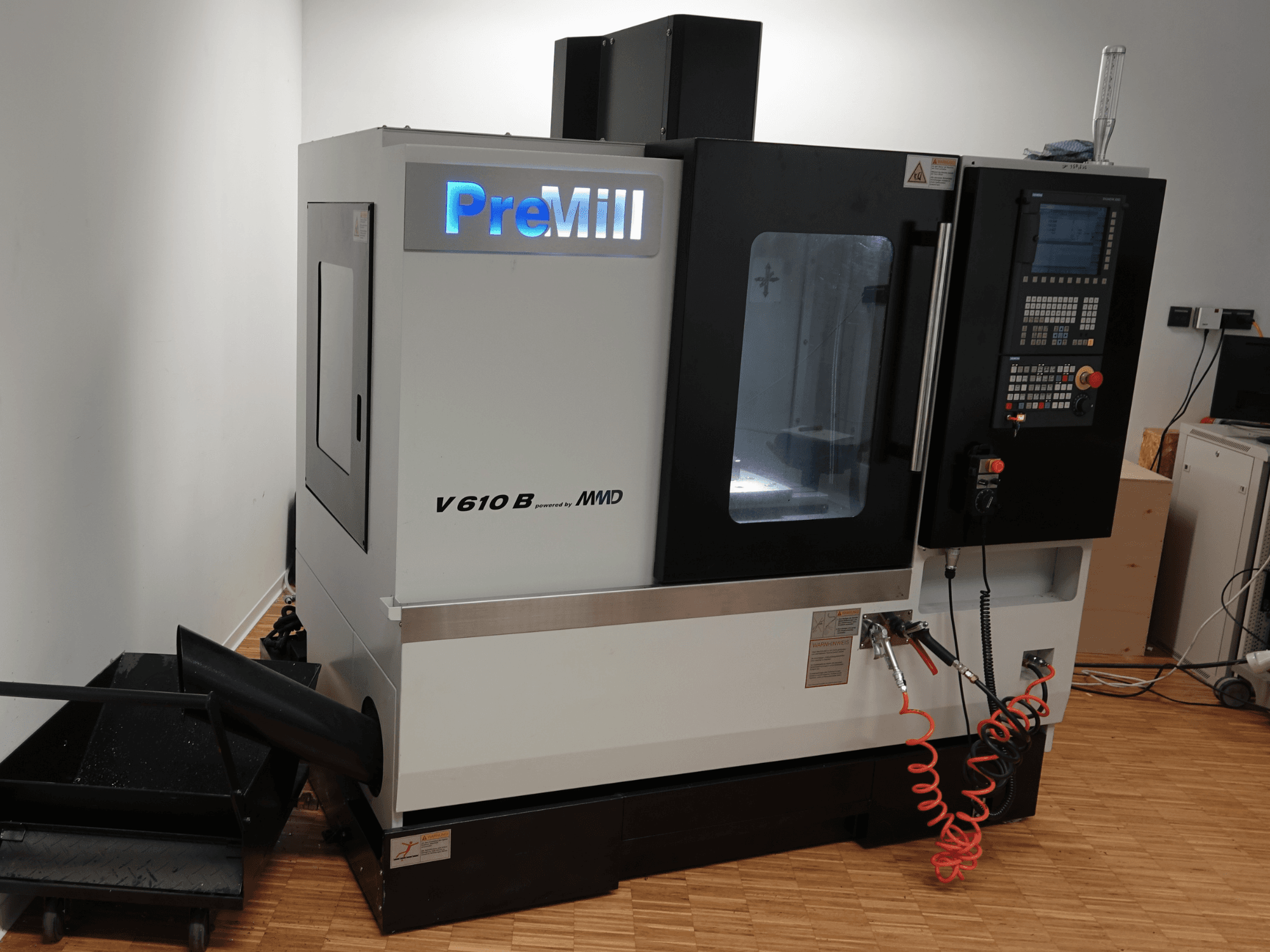 PreMill V 610 B dikey işleme merkezi, önden görünüm; kontrol paneli, soğutma sıvısı sistemi ve bağlı hava hortumları ile birlikte.