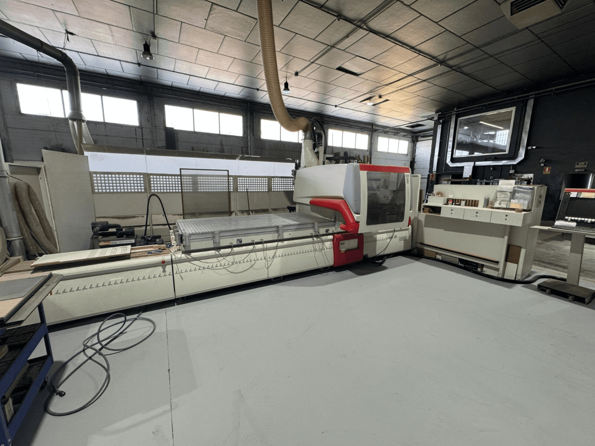 Bir atölyede CNC makinesi, kırmızı desenli önden görünüm, hassas kesim için kontrol paneli ve çalışma yüzeyi ile donatılmıştır.