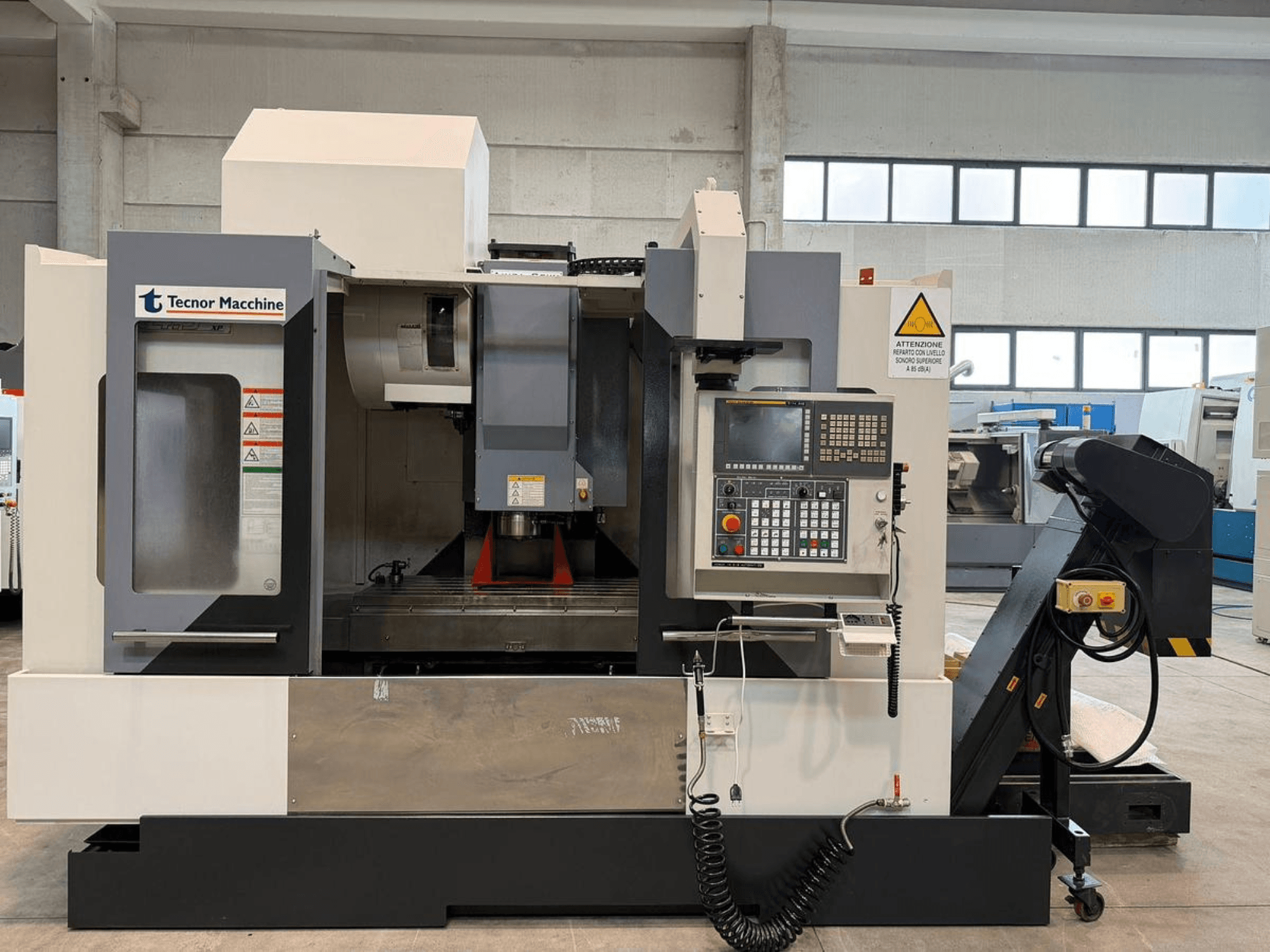 Tecnor Machine CNC freze makinesi, önden görünüm, düğmeli kontrol paneli, uyarı etiketleri ve takım tutucu.