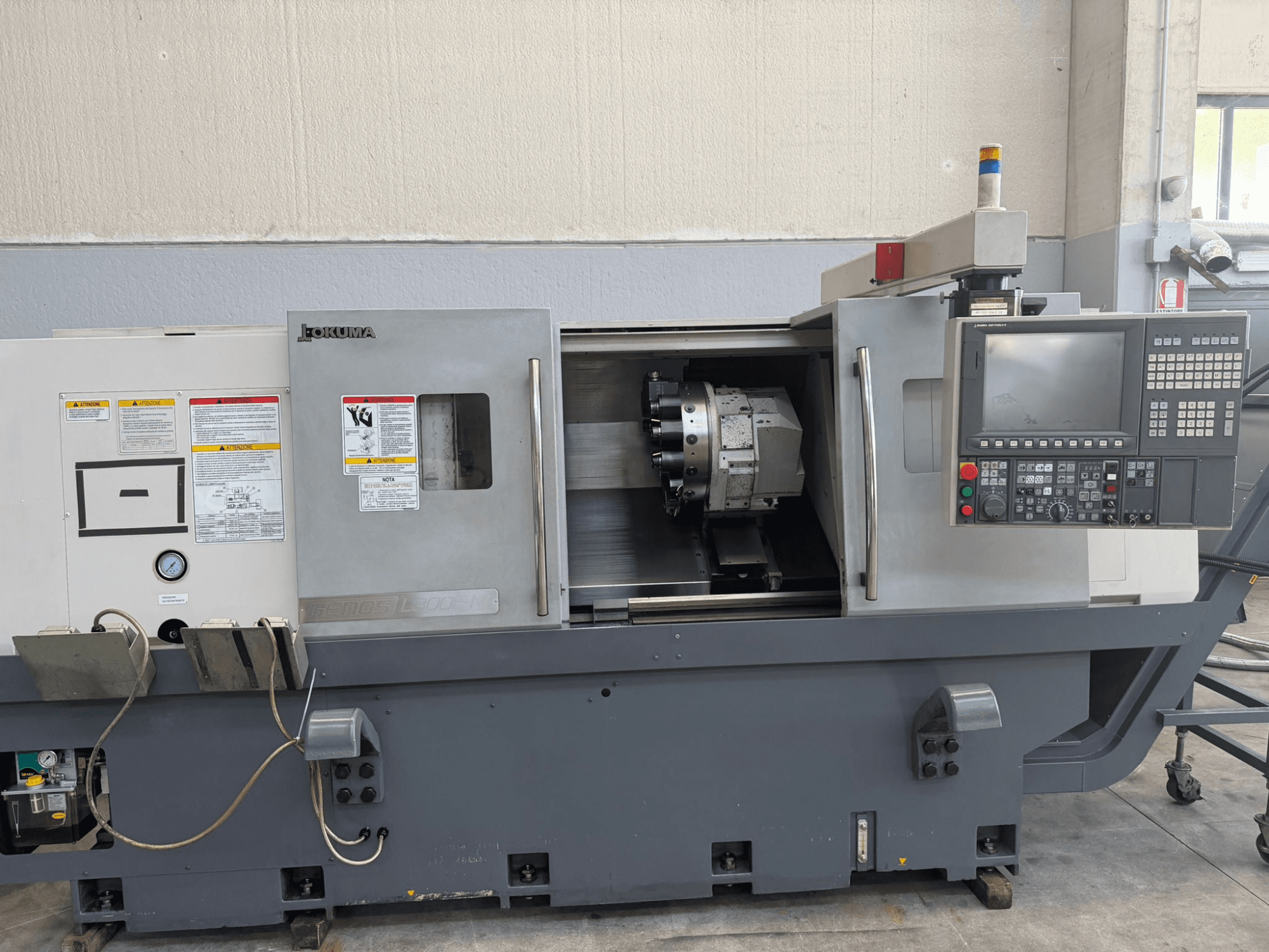 Okuma CNC torna makinesi, önden görünüm, kontrol panelini, kesici takım tutucusunu ve yan taraftaki güvenlik uyarılarını gösterir.