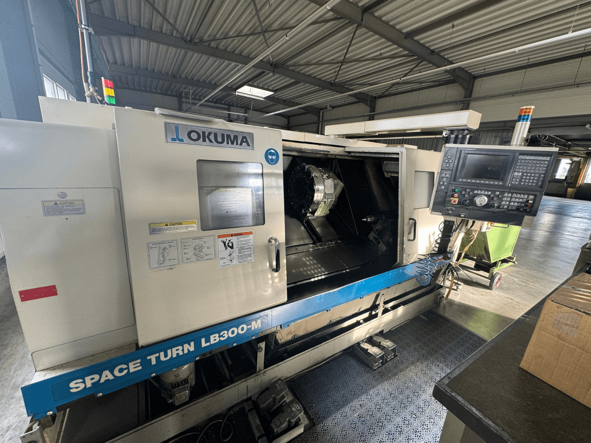 Okuma Space Turn LB300-M CNC torna tezgahının önden görünümü, kontrol paneli ve iç işleme alanını gösteren açık kapı.