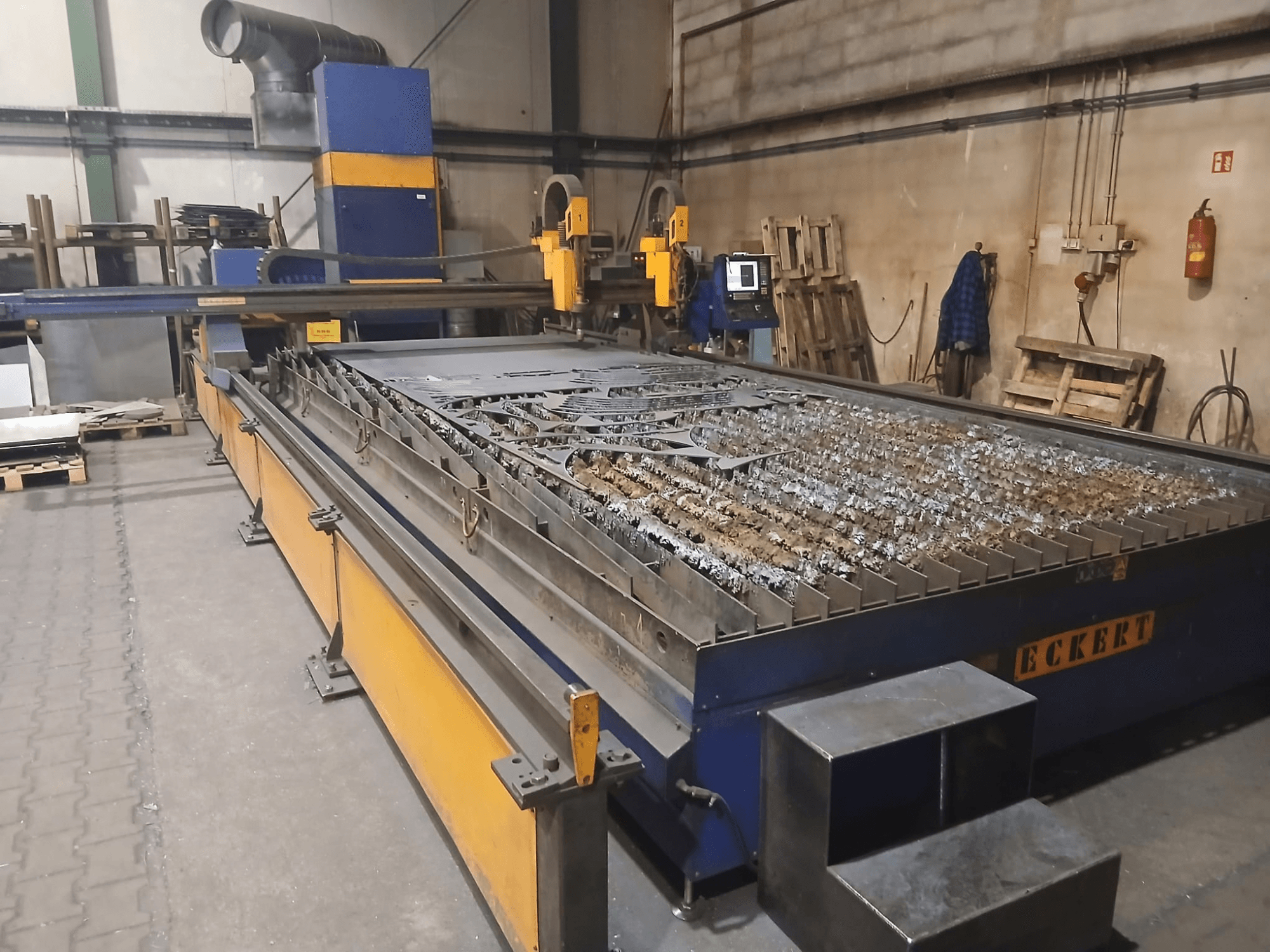 ECKERT JANTAR 2 plazma kesme makinesinin önden görünümü; metal parçaların bulunduğu geniş bir kesme masası ve çalıştırma kumandaları ile donatılmıştır.