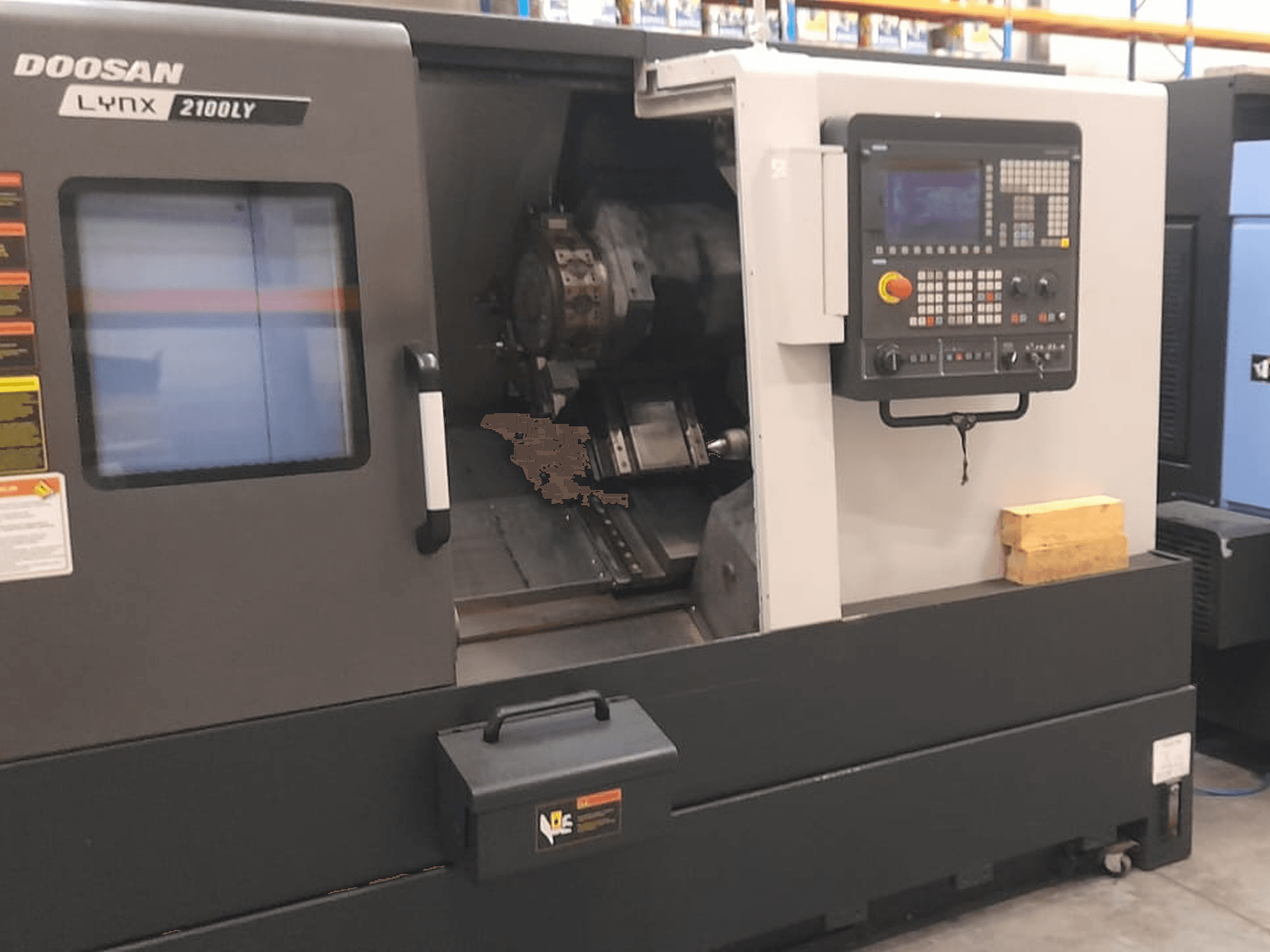 Doosan Lynx 2100LY CNC torna tezgahı, kontrol paneli, takım tutucu ve iç çalışma alanını gösteren önden görünüm; teknik etiketler görülebilir.