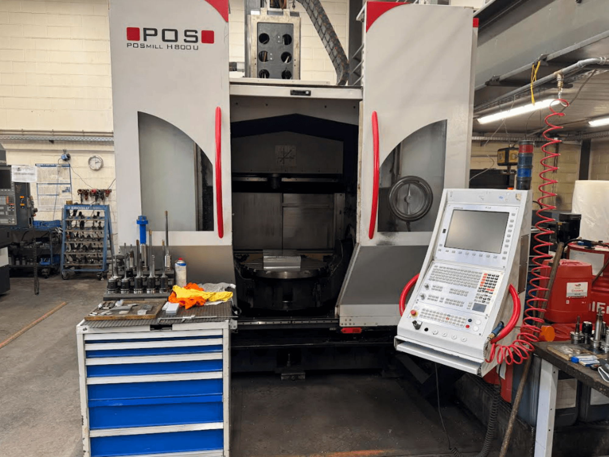 POSMILL H800 U CNC makinesinin önden görünümü, kontrol panelini ve yakınındaki alet ve ekipmanlarla birlikte çalışma alanını sergiliyor.