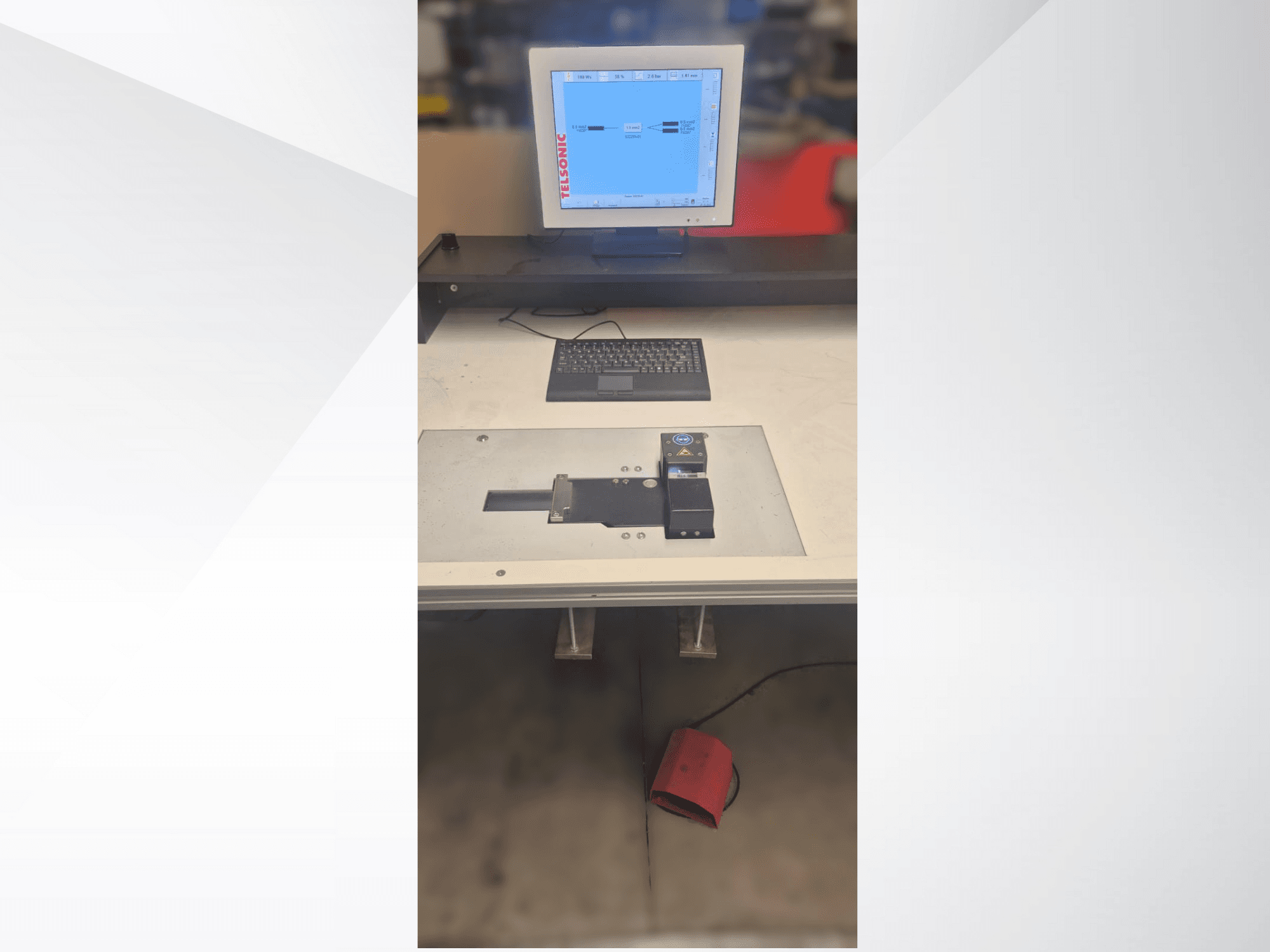 Bilgisayar monitörü, klavye ve bir düğme ile yeşil ışık içeren kontrol paneline sahip bir test istasyonunun yukarıdan aşağıya görünümü.