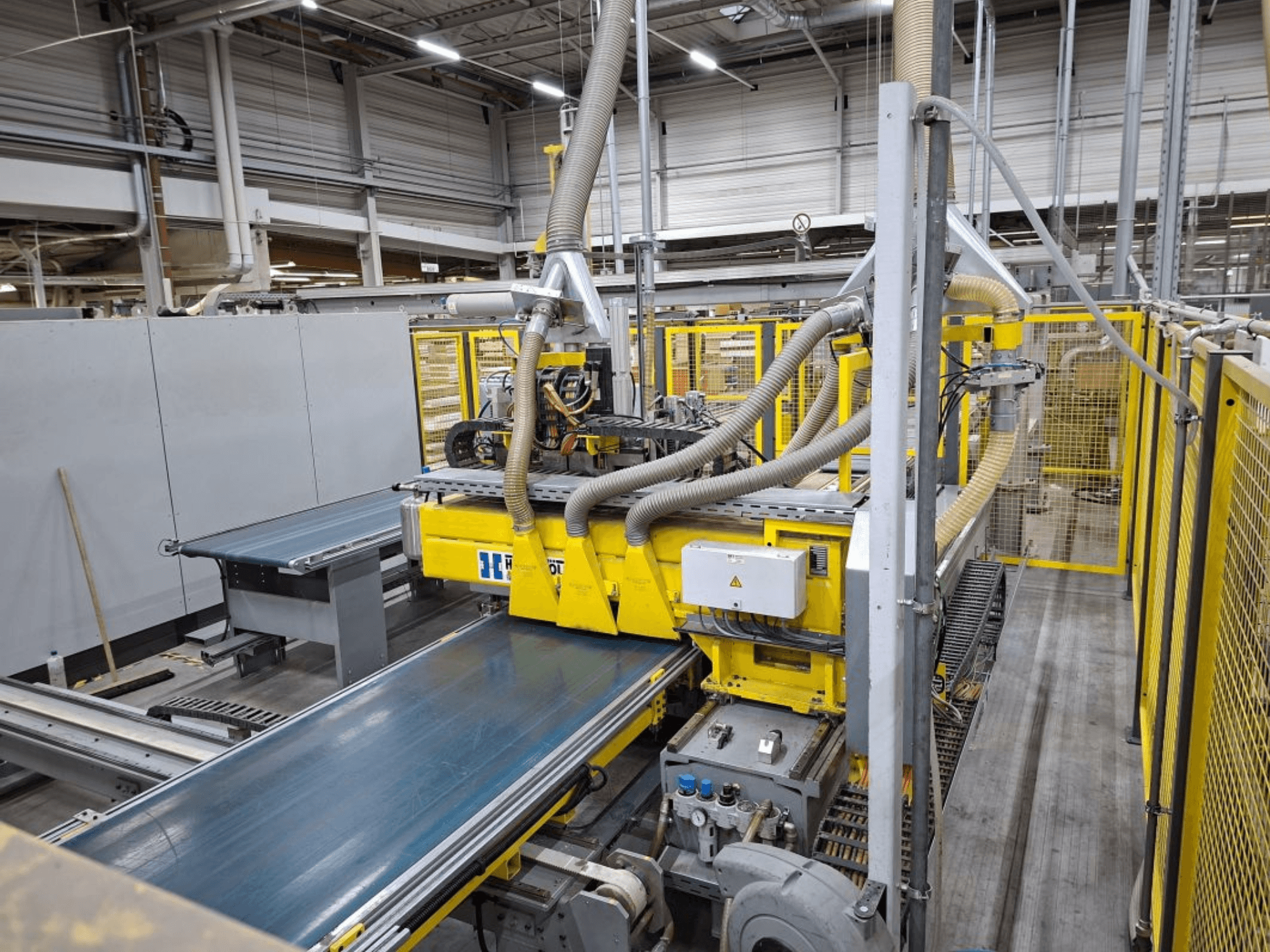 Yandan görünümlü endüstriyel konveyör sistemi, sarı makineler, kontrol paneli ve üretim için hortum eklentileri.