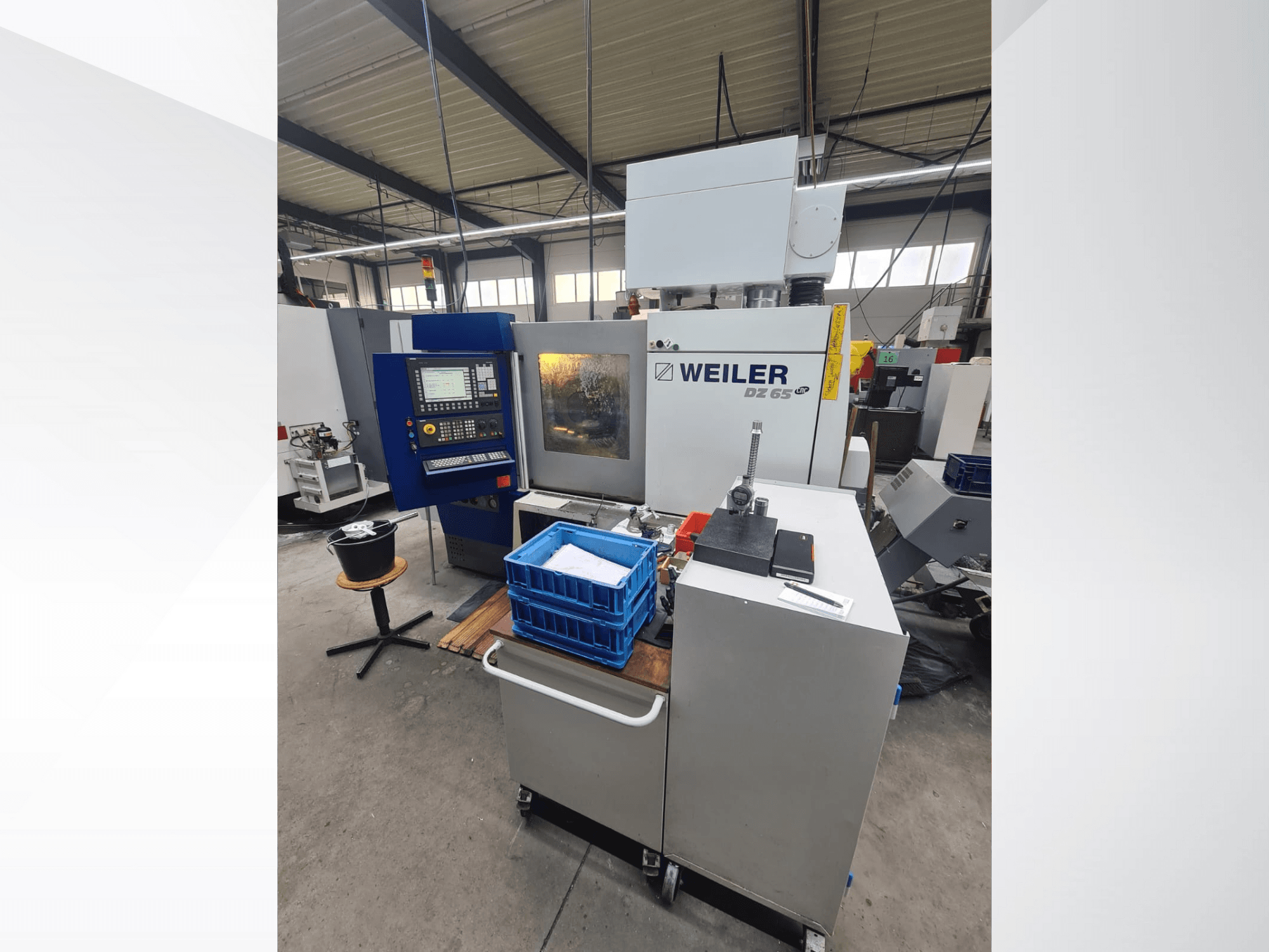 Atölyedeki Weiler DZ 65 CNC makinesi, kontrol paneli, aletler ve mavi saklama kutularının göründüğü önden görünüm.