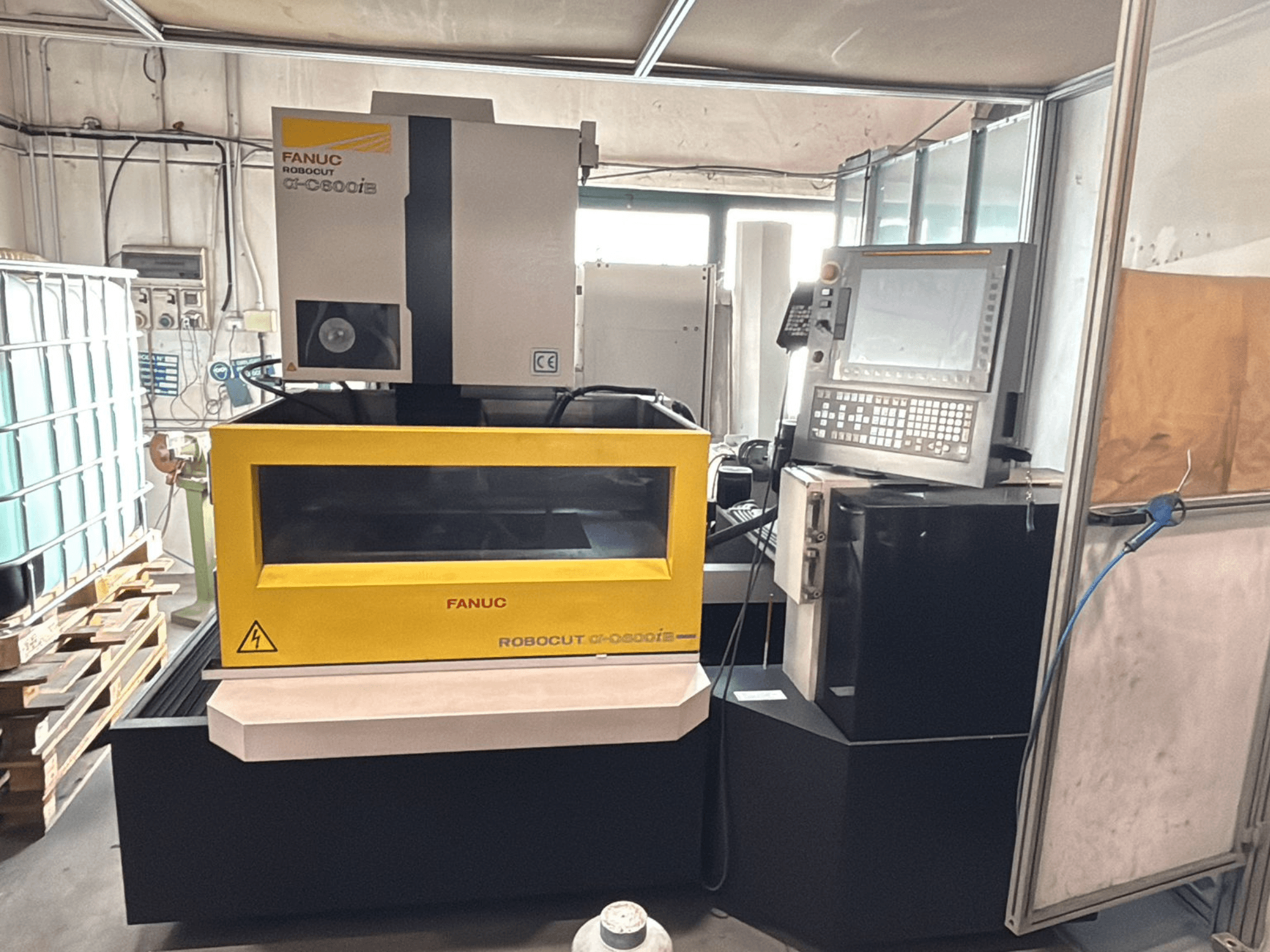 Kontrol paneli ve ekranı sergileyen sarı kasalı bir FANUC Robocut α-0iE CNC makinesinin önden görünümü.