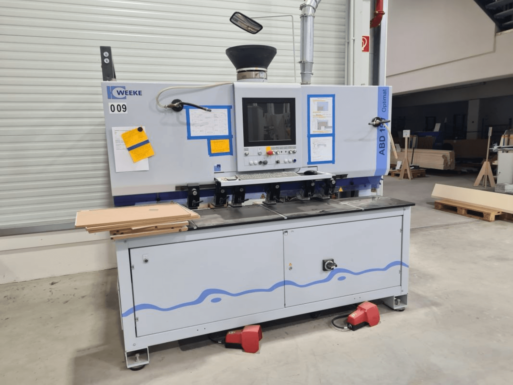 HOMAG WEEKE OPTIMAT ABD150 çok milli delme makinesi, önden görünüm, kontrolleri ve istiflenmiş ahşap panelleri gösteriyor.